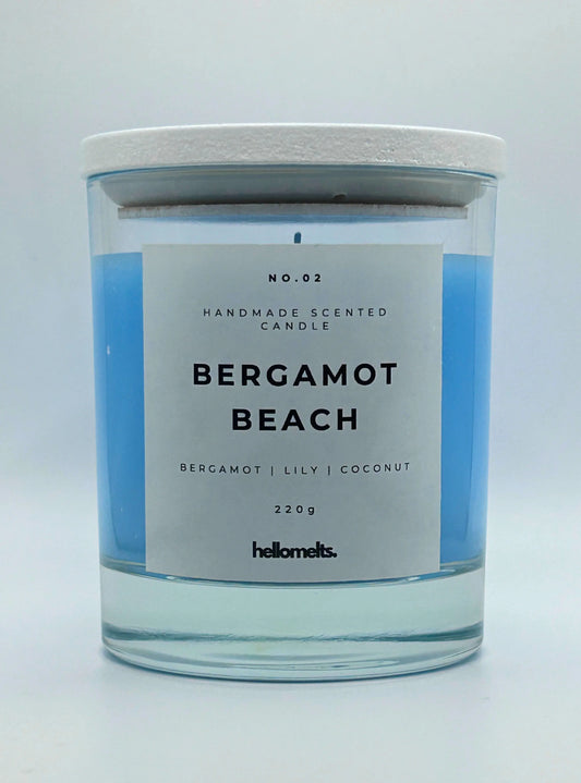 Bergamot Beach 220g candle, with lid on, by Hellomelts, infused with refreshing bergamot, lily and a hint of coconut, in a beach-inspired blue wax.