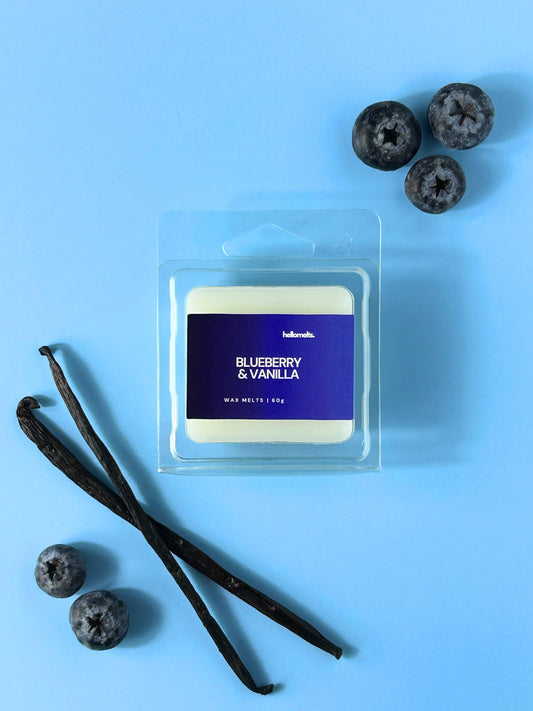 Blueberry & Vanilla wax melt bar by Hellomelts on a pale blue backdrop styled with blueberries and natural vanilla pods