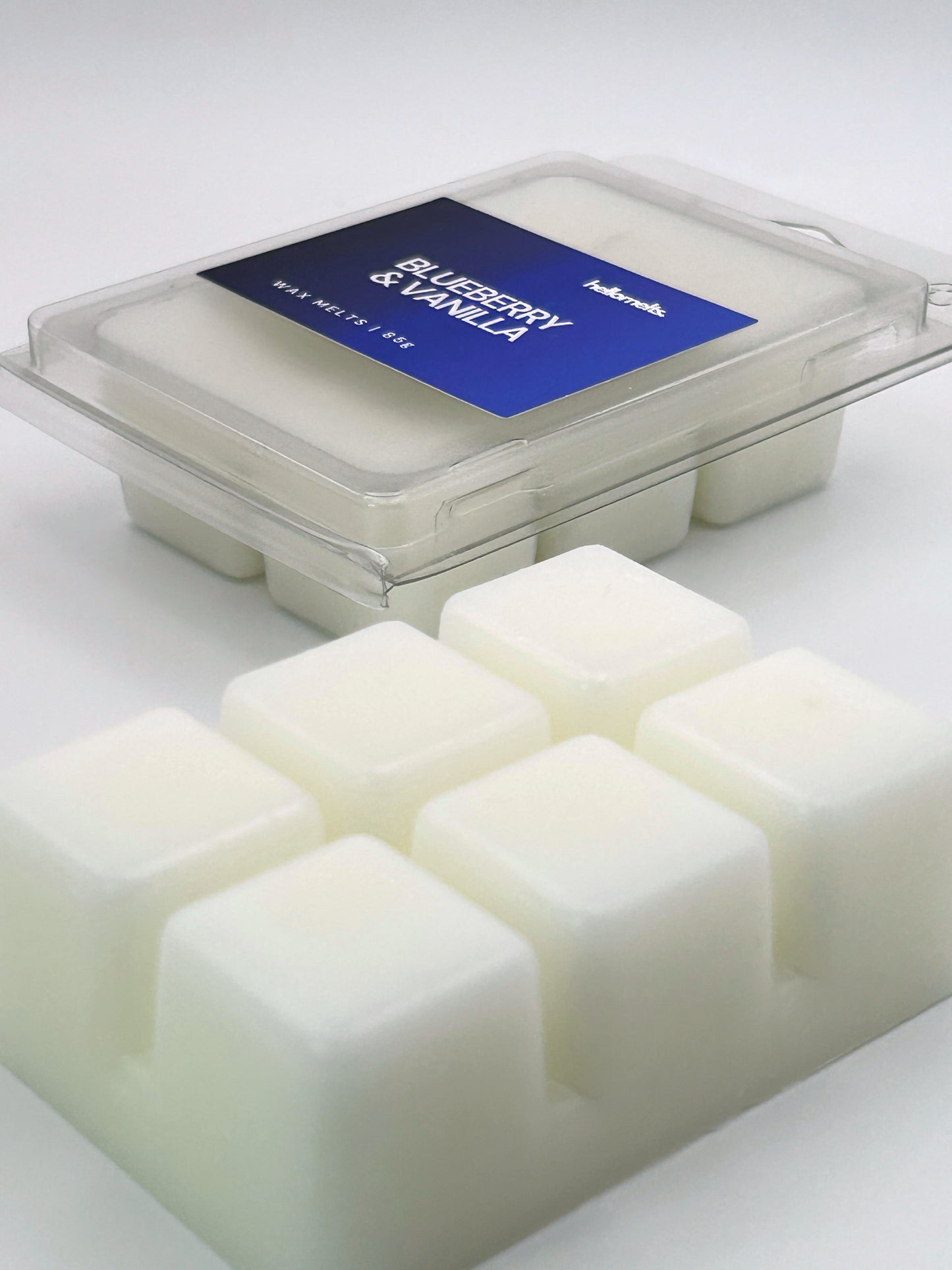 Angled shot of Blueberry & Vanilla 85g wax melt bar in front of its packaging, part of the Summer Collection by Hellomelts