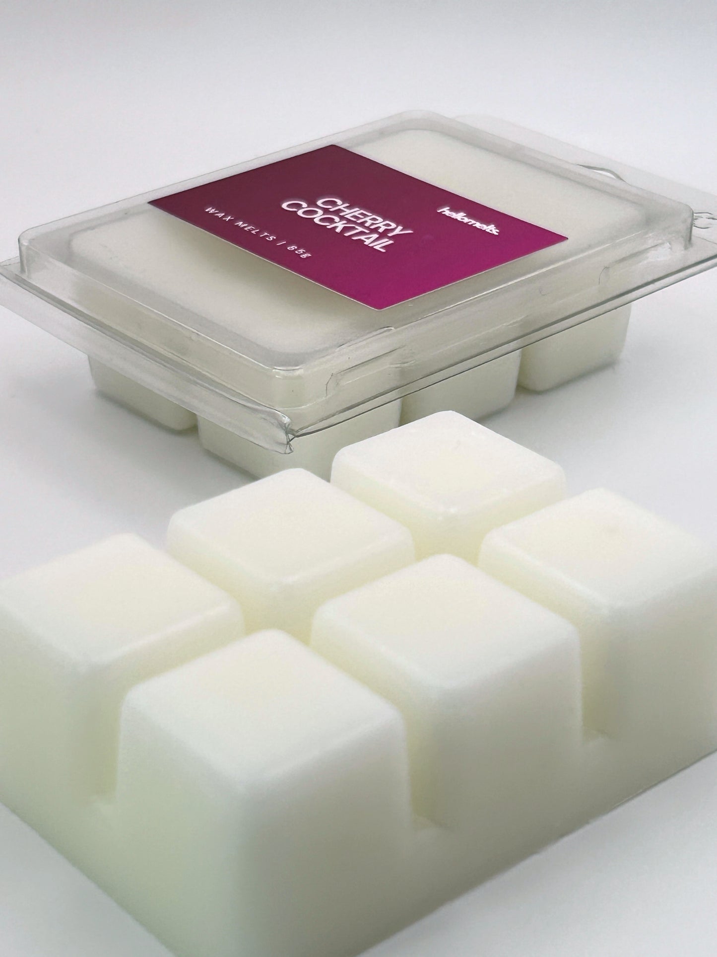 Angled shot of Cherry Cocktail 85g wax melt bar in front of its packaging, part of the Hellomelts Summer Collection