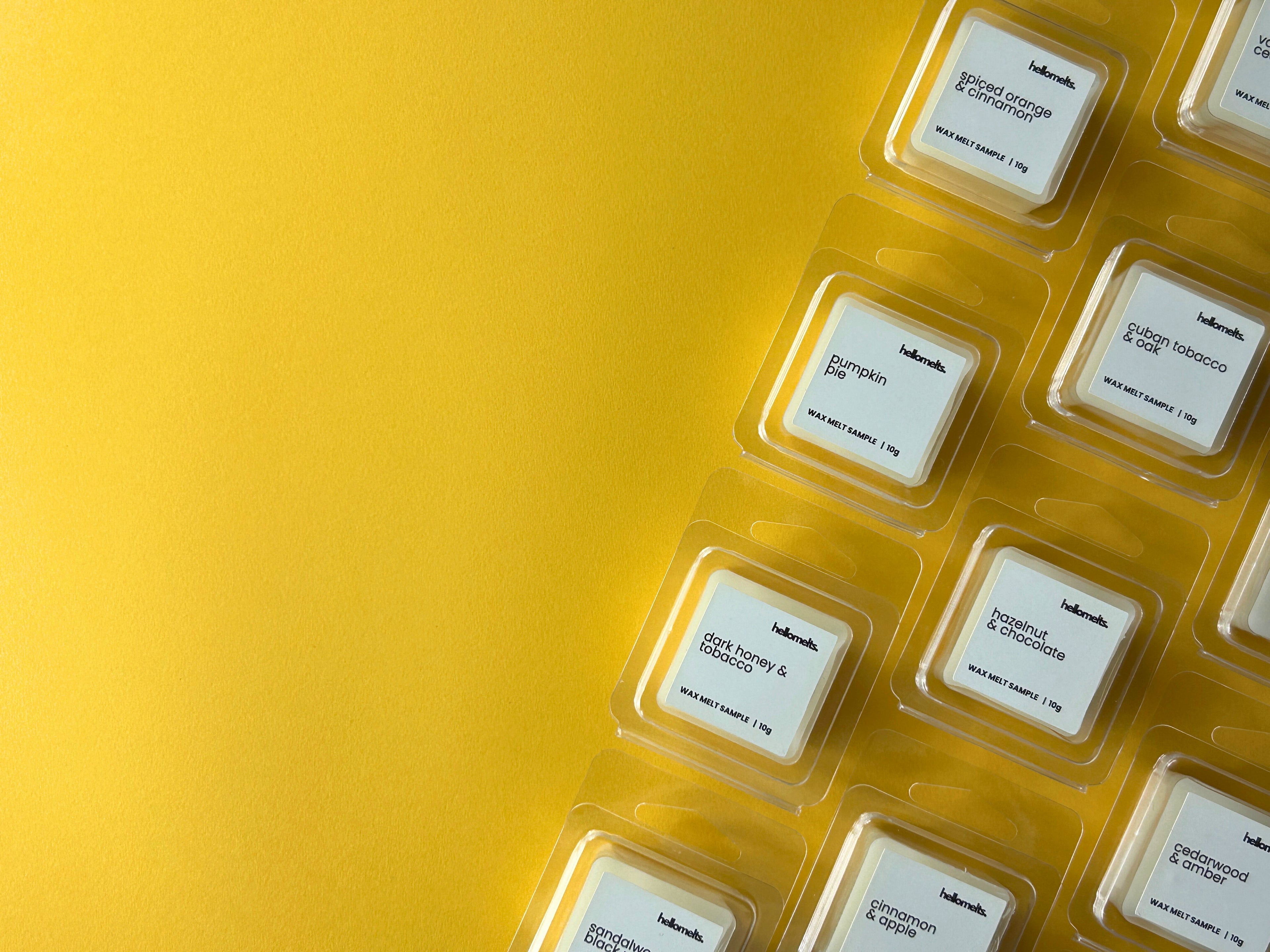 Flatlay of Hellomelts free 10g wax melt samples from the Autumn Collection, arranged in clamshell packaging on a yellow background, used for website banner promoting free wax melt samples