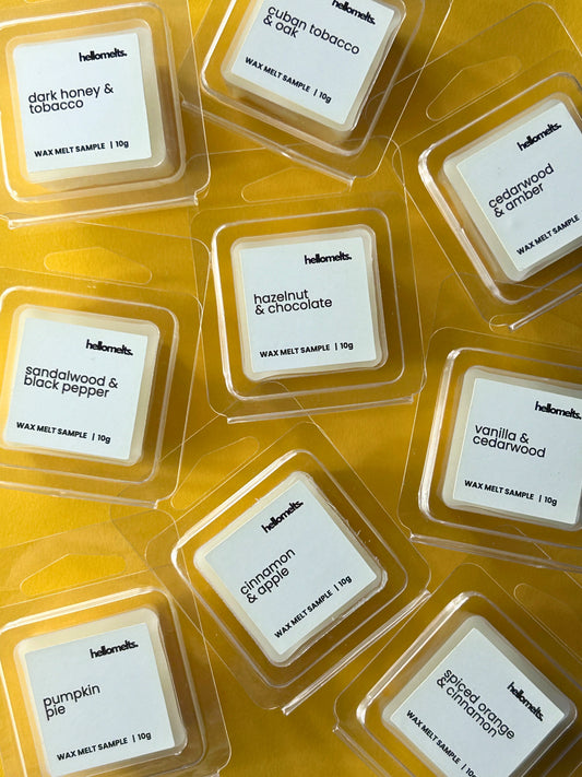 Selection of Hellomelts Autumn Collection free 10g wax melt samples in clamshell packaging, including Pumpkin Pie, Spiced Orange & Cinnamon, Cinnamon & Apple, and other seasonal scents, displayed on yellow background