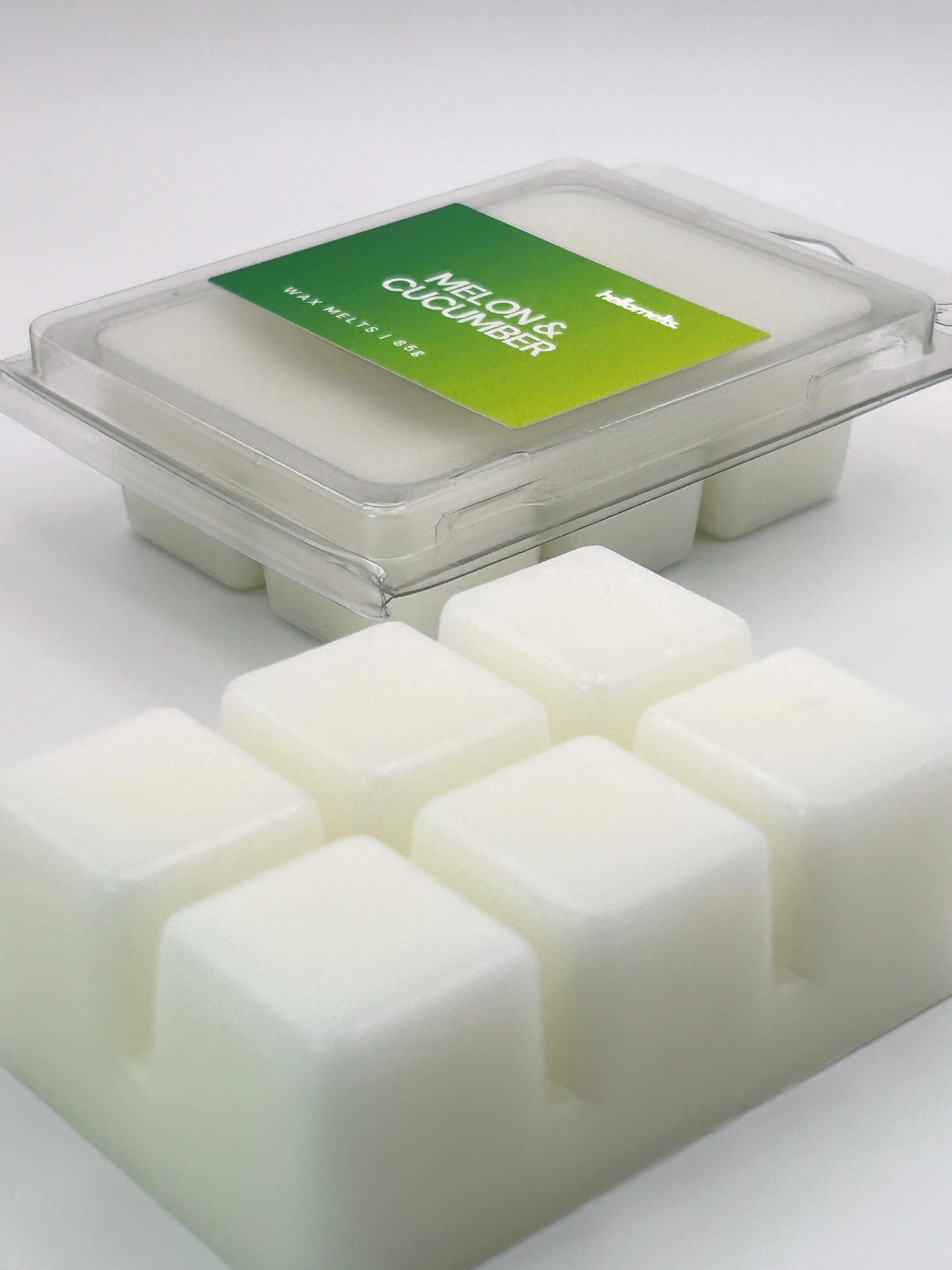 Angled shot of Melon & Cucumber 85g wax melt bar in front of its packaging, part of the refreshing Summer Collection by Hellomelts