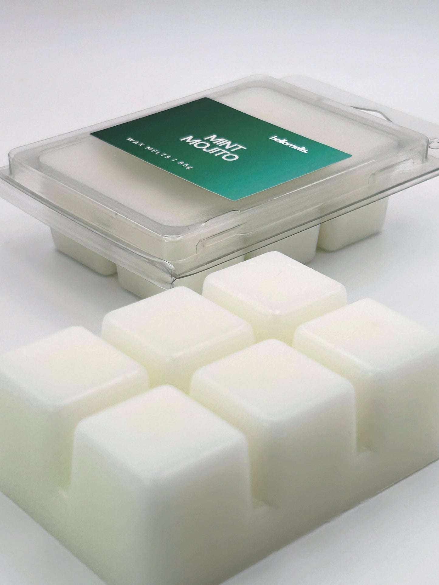 Angled shot of Mint Mojito 85g wax melt bar in front of its packaging, part of the Summer Collection by Hellomelts