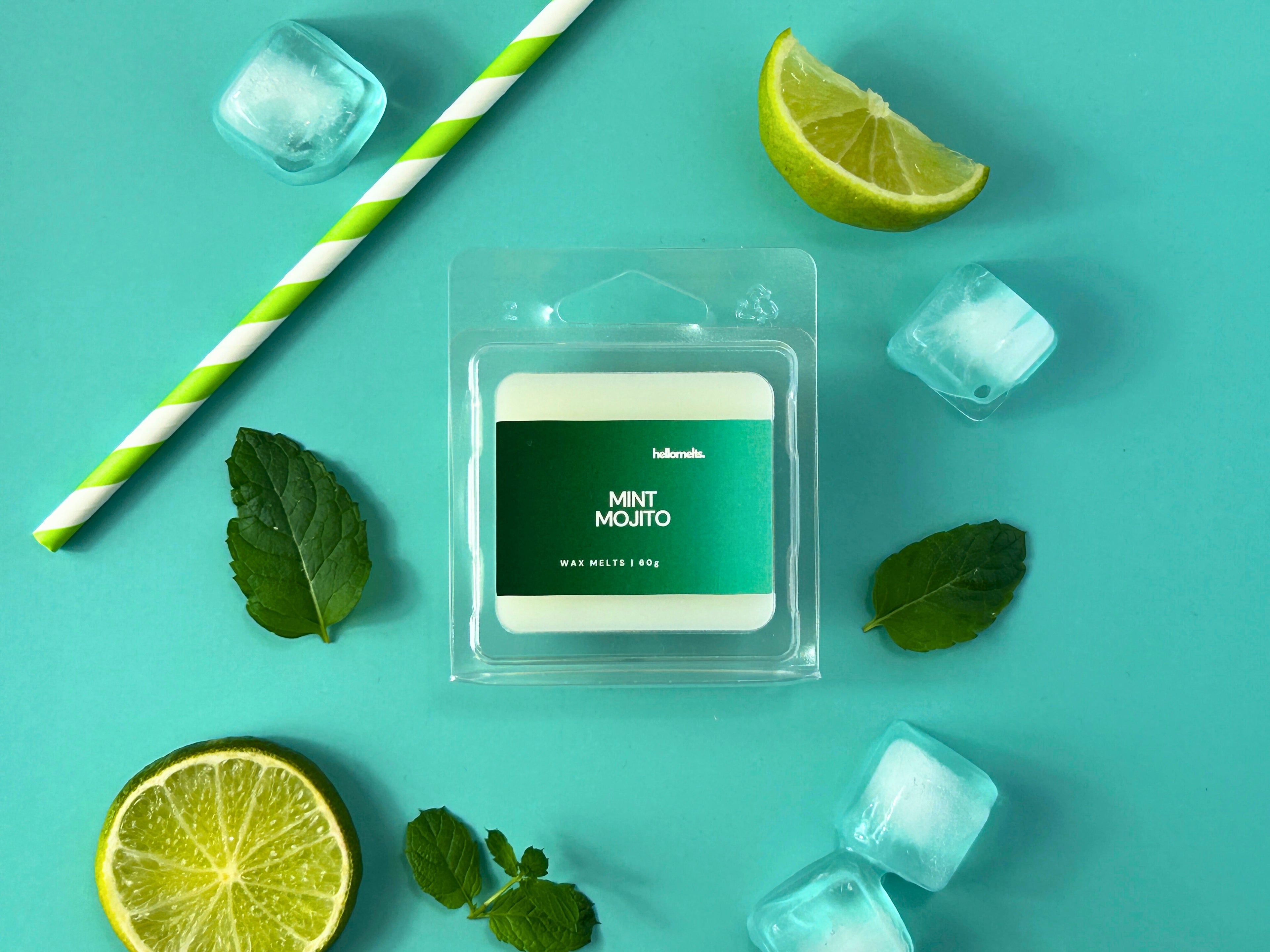 Mint Mojito 60g wax melt bar by Hellomelts, surrounded by lime slices, ice cubes, mint leaves, and a green paper straw on a mint/teal background, styled for the Summer Collection