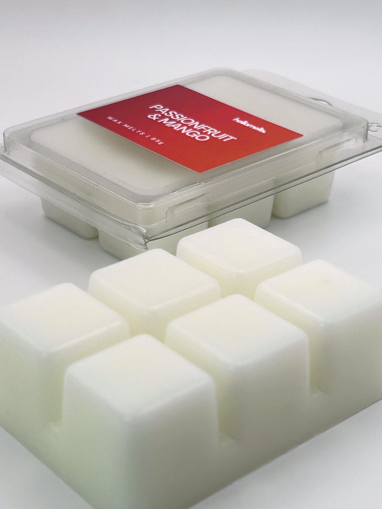 Angled shot of Passionfruit & Mango 85g wax melt bar in front of its packaging, part of the Summer Collection by Hellomelts