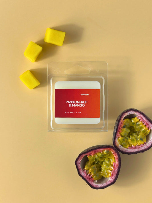 Passionfruit & Mango wax melts by Hellomelts, presented in clear clamshell packaging on a soft neutral backdrop with fresh passionfruit halves and mango cubes, part of the Summer Collection