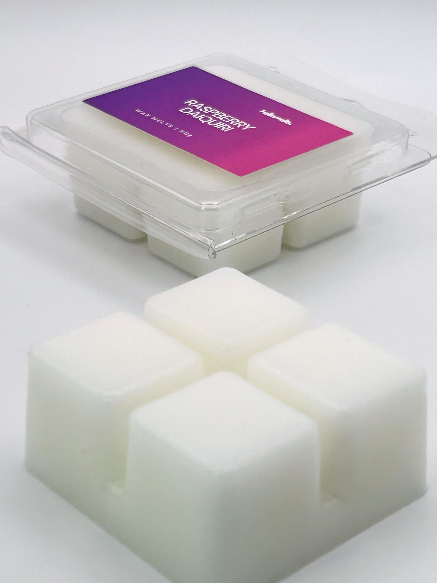 Angled shot of Raspberry Daiquiri 60g wax melt bar in front of its packaging, part of the Summer Collection by Hellomelts