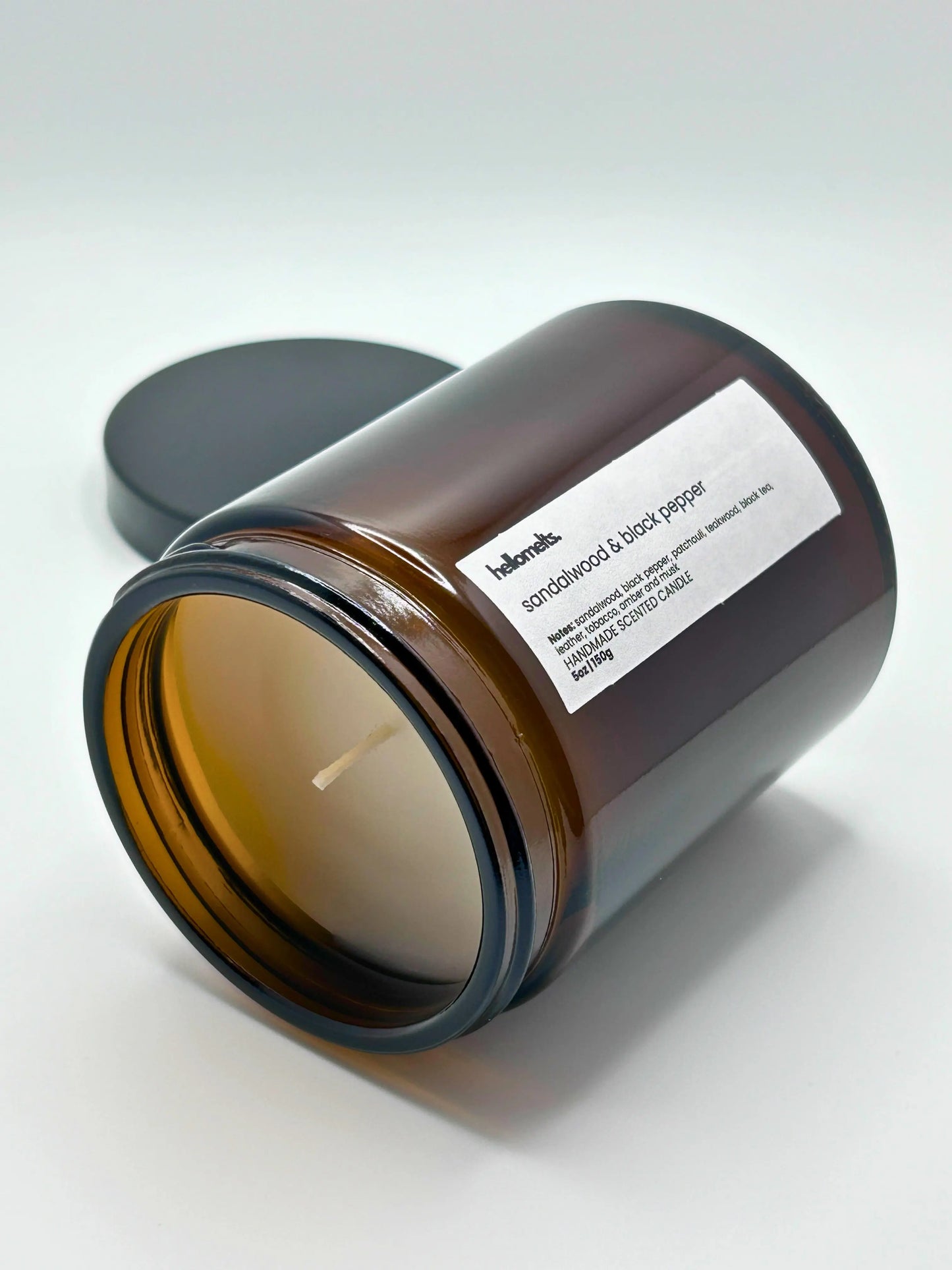 Sandalwood & Black Pepper candle by Hellomelts lying down with the wick facing forward, part of the autumn collection.