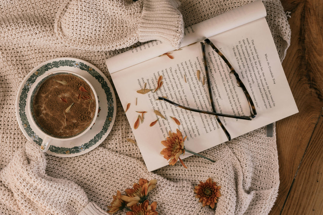 Cosy winter evening at home with a warm drink and open book, creating a calm and comforting atmosphere