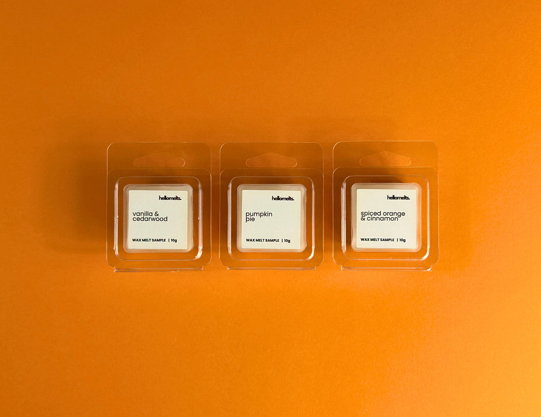 Three 10g Hellomelts wax melt samples with Vanilla & Cedarwood, Pumpkin Pie, and Spiced Orange & Cinnamon, displayed on a bright orange background from the Autumn Collection, promoting the updated free wax melt sample sign-up page