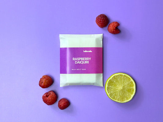 Raspberry Daiquiri wax melt bar from the Hellomelts 2025 Summer Collection, styled with raspberries and lime on a purple background.