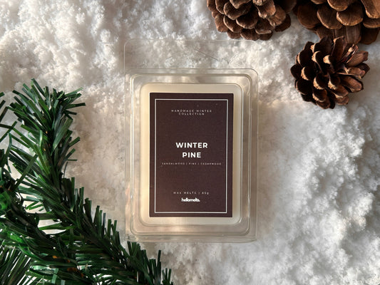 Winter Pine wax melts from the Hellomelts Winter Collection styled on a snowy background with pinecones and evergreen foliage