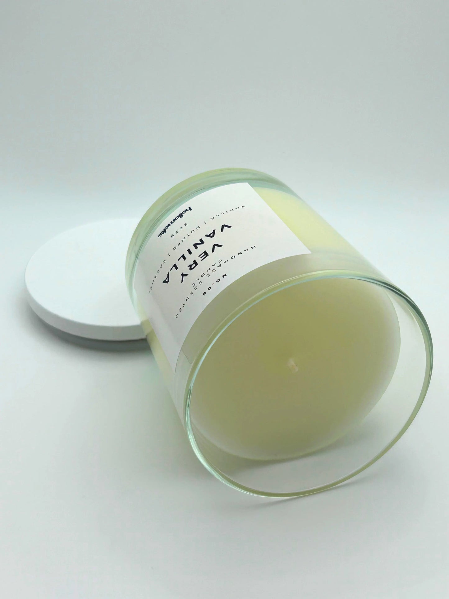 Very Vanilla 220g candle by Hellomelts, on its side, infused with the warm scents of vanilla, nutmeg, and caramel, showcased in a simple white wax.