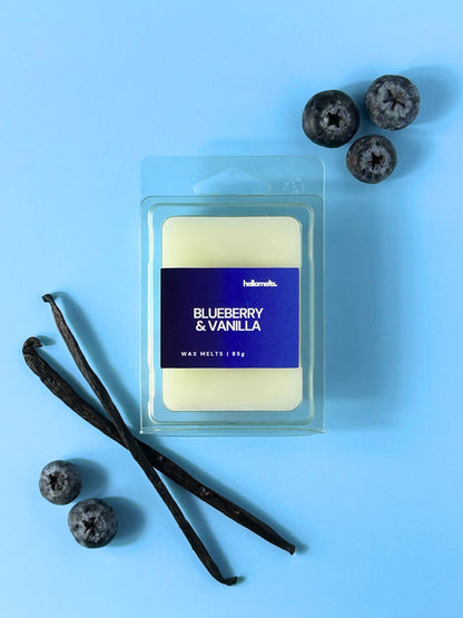 Blueberry & Vanilla wax melt bar by Hellomelts displayed on a light blue background with fresh blueberries and whole vanilla pods