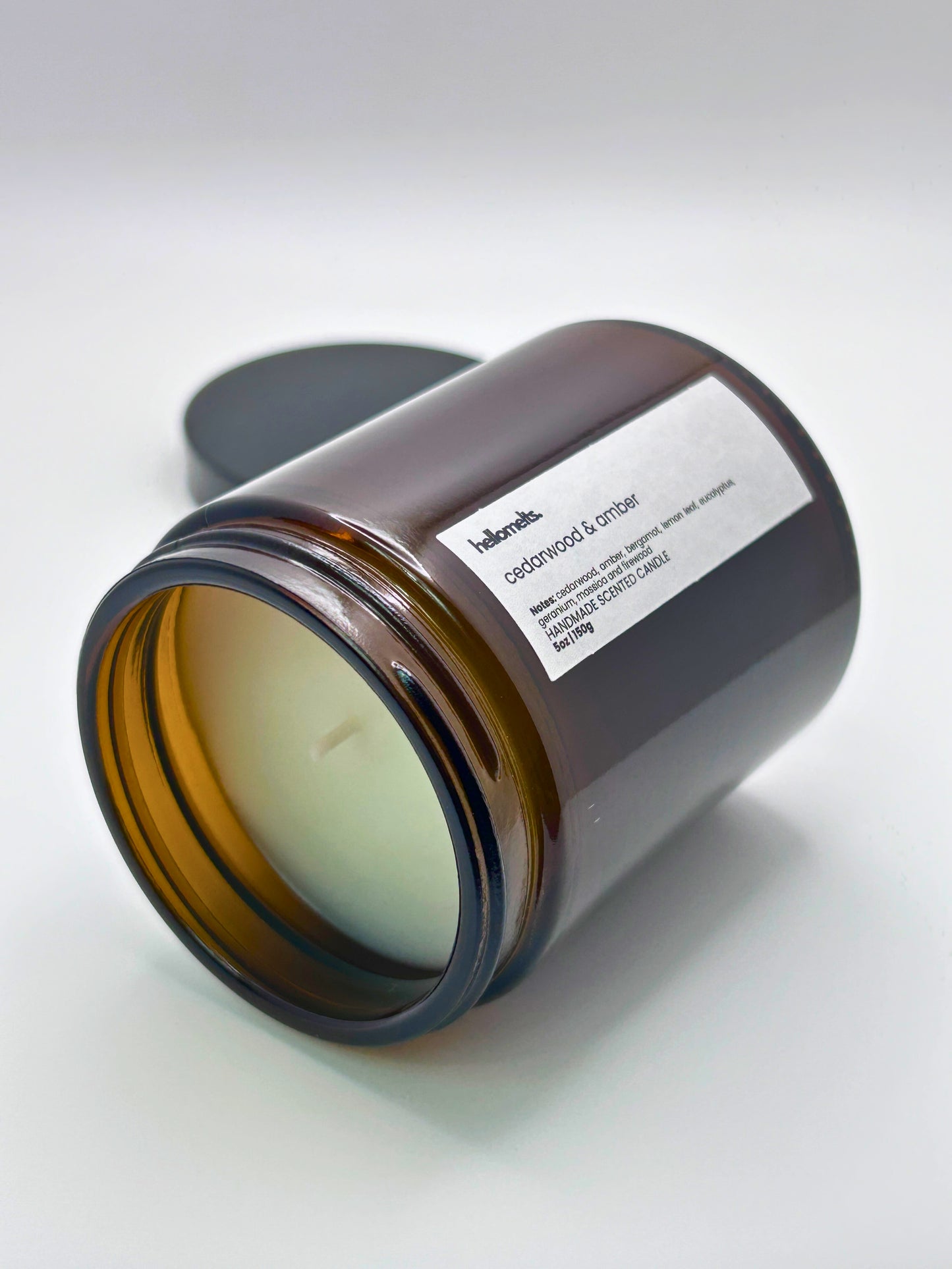 Cedarwood &  Amber autumn scented candle by Hellomelts lying on its side with the wick facing forward, part of the Autumn Collection