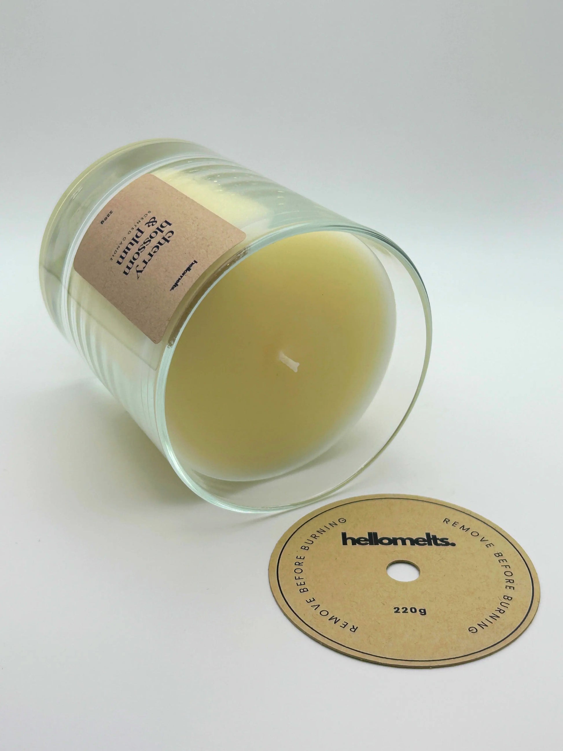 Cherry Blossom & Plum candle lying flat with the wick cover removed and placed beside it, showing the smooth wax finish by Hellomelts.