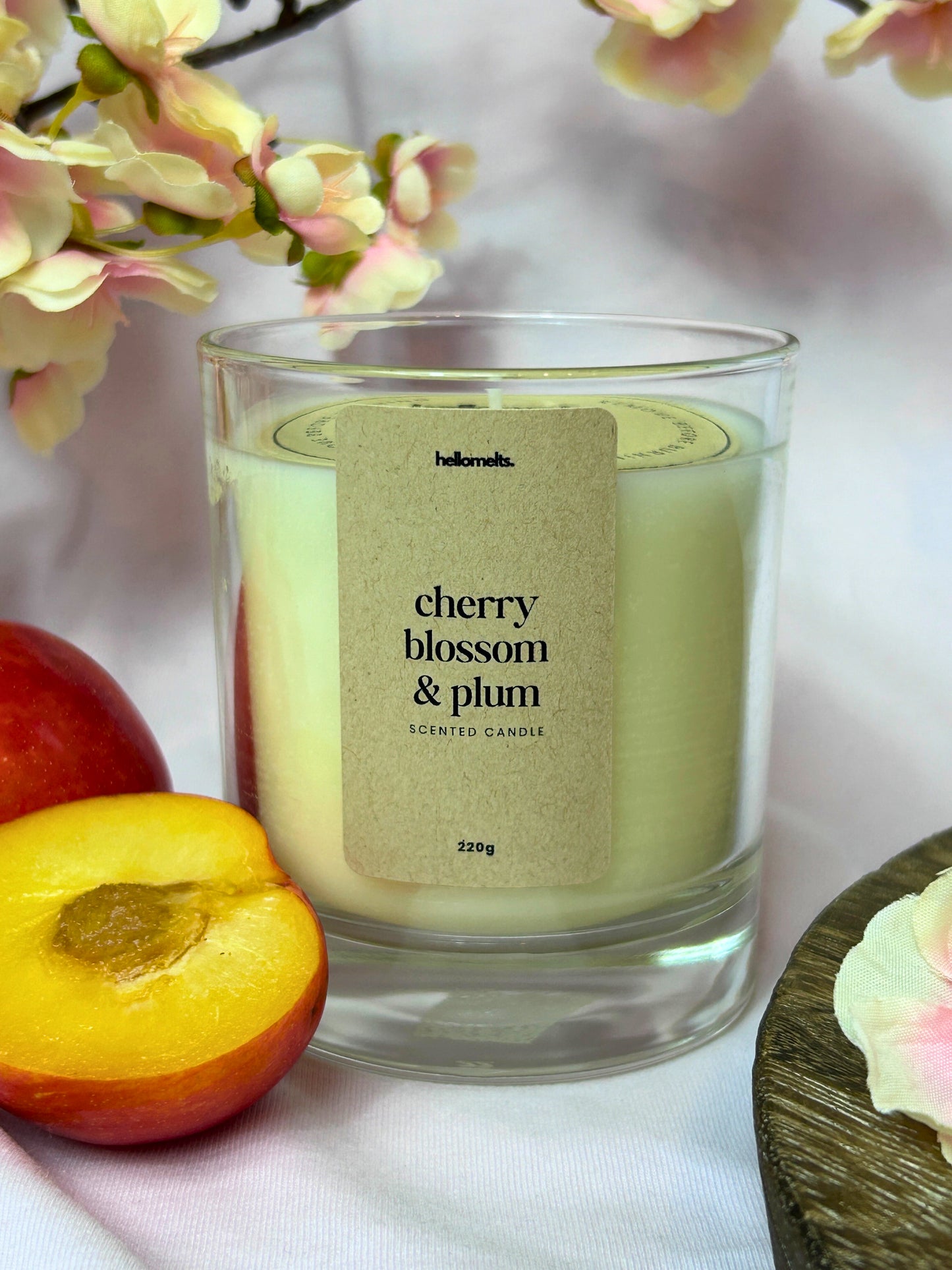 Cherry Blossom & Plum scented candle in clear glass jar with pink blossom branch and fresh plum props from the Hellomelts Spring Collection