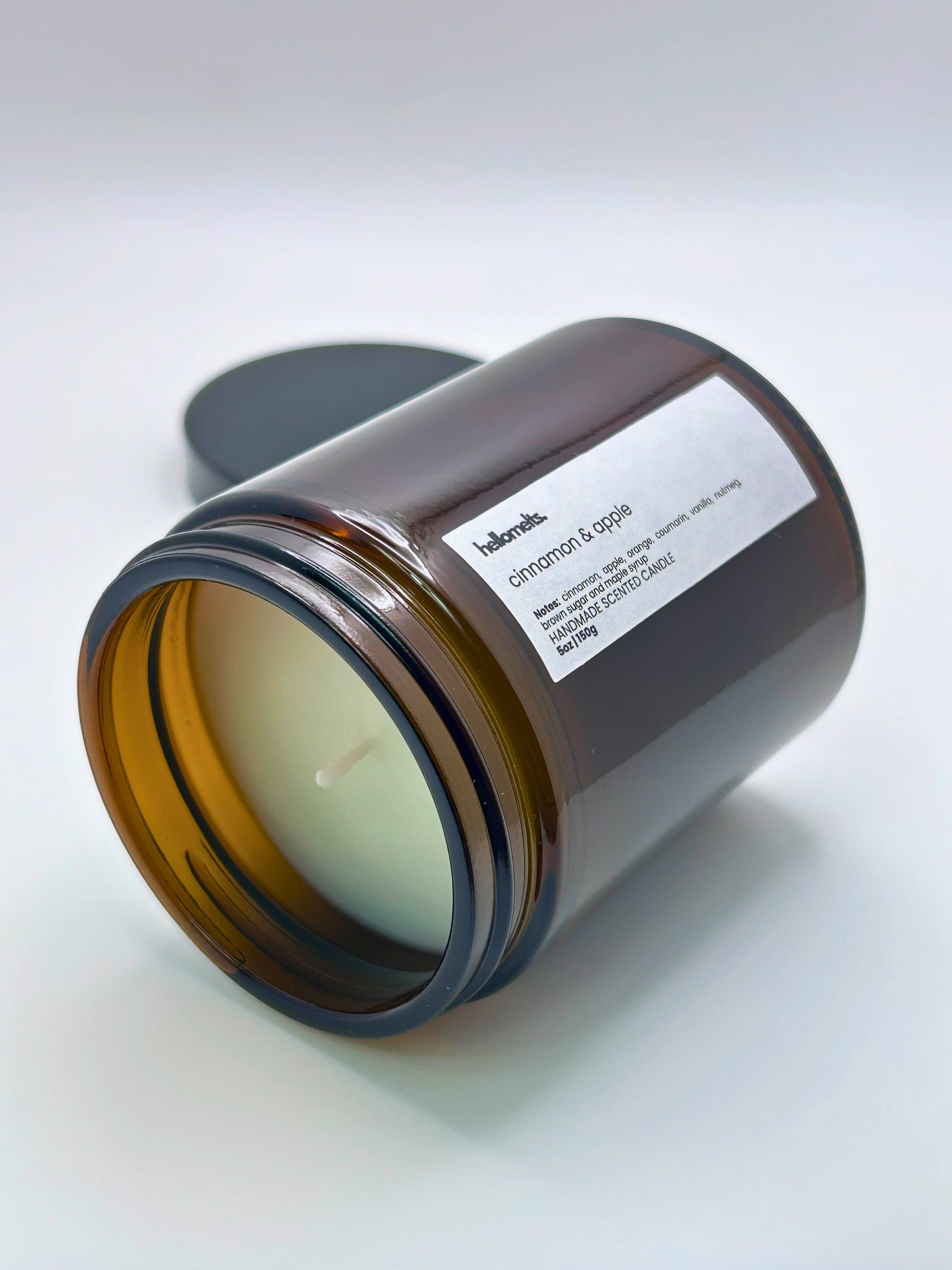 Cinnamon & Apple autumn scented candle by Hellomelts lying on its side with the wick facing forward, part of the Autumn Collection