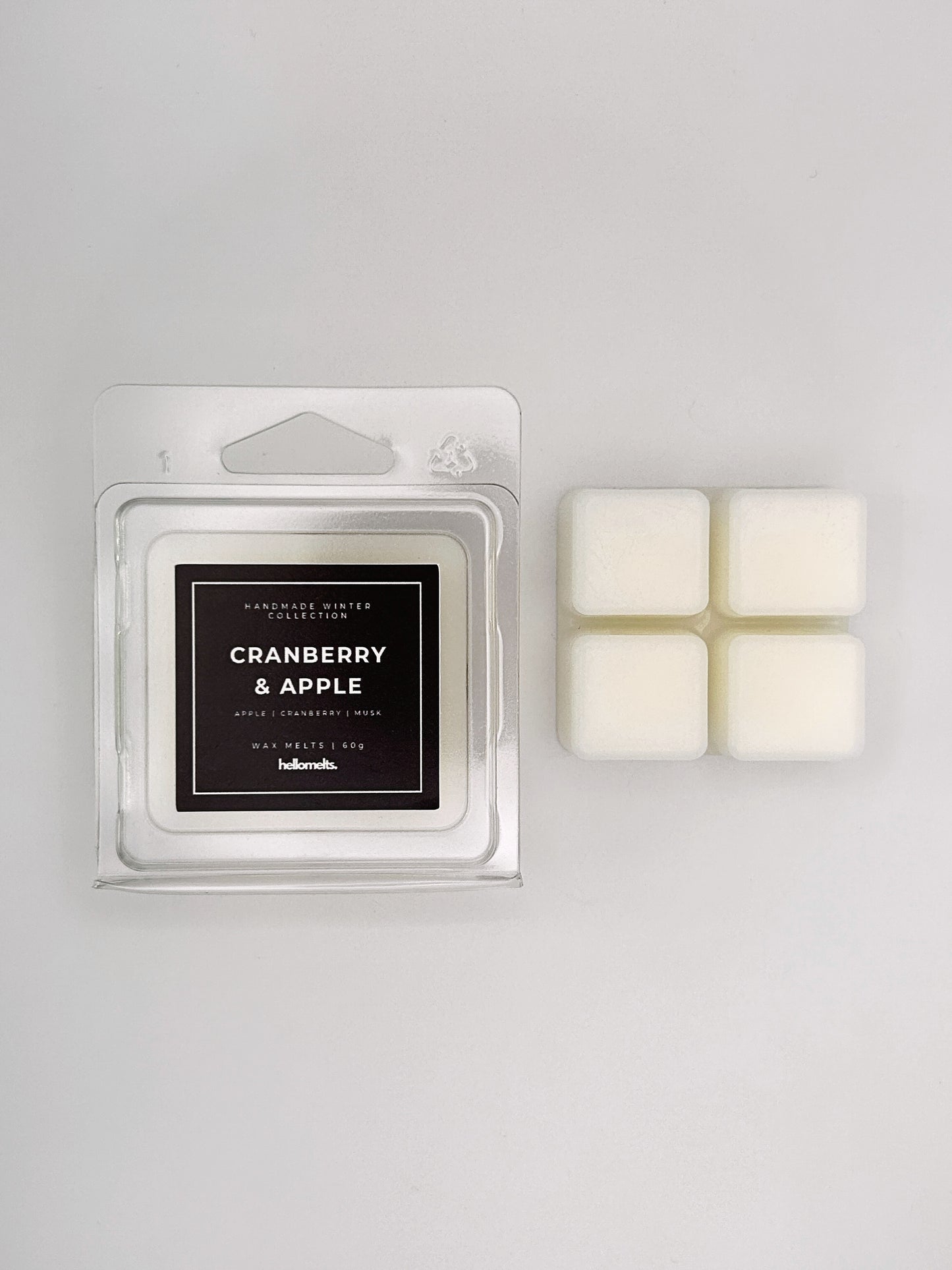 Cranberry & Apple 60g wax melt clamshell placed beside four wax cubes from the Hellomelts Winter Collection