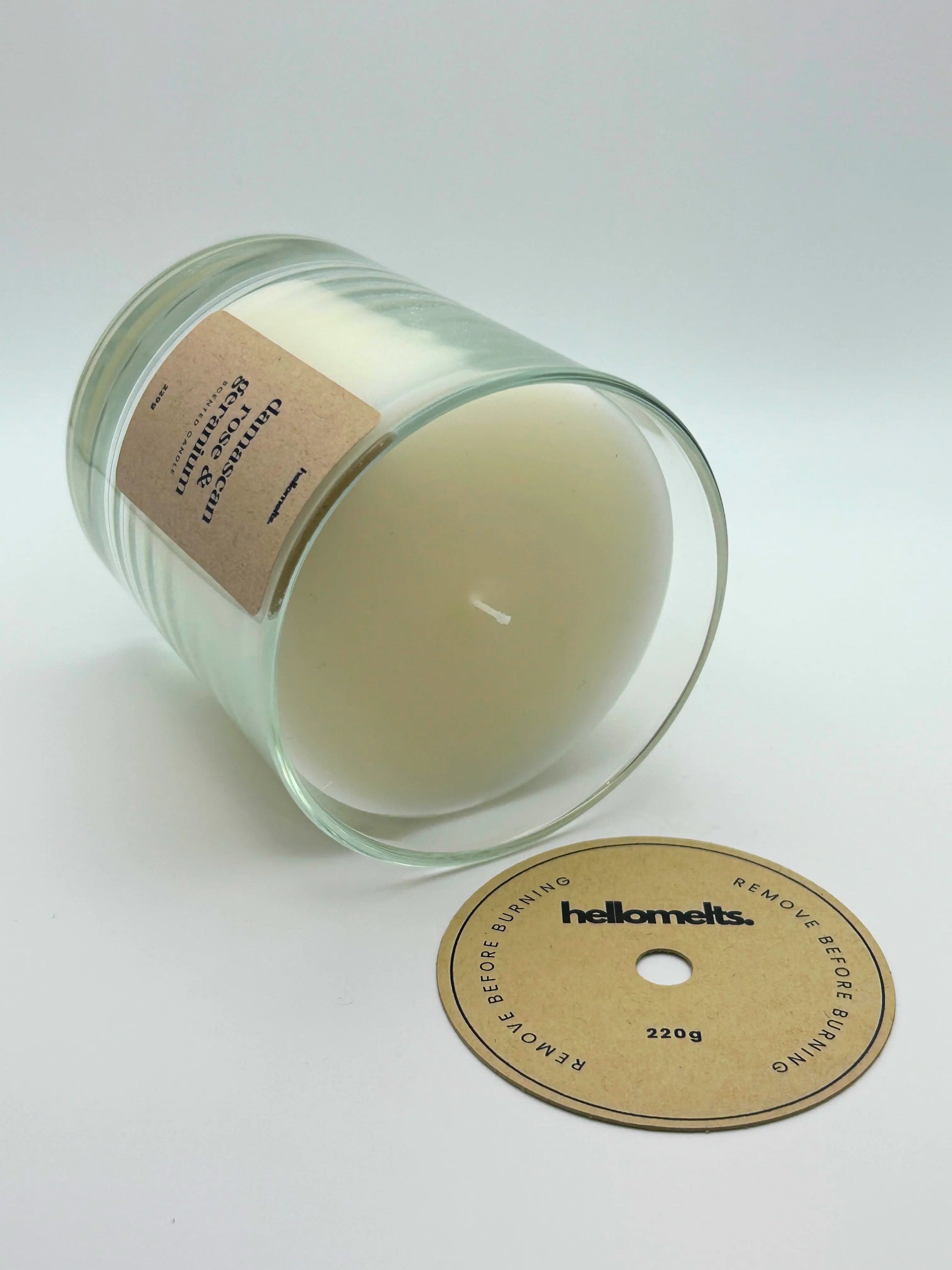 Damascan Rose & Geranium candle lying flat with the wick cover removed and placed beside it, showing the smooth wax finish by Hellomelts.