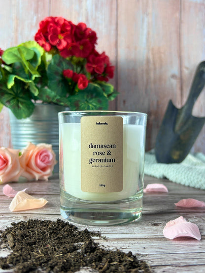 Damascan Rose & Geranium scented candle by Hellomelts styled with soft pink rose petals and greenery in a spring lifestyle setting