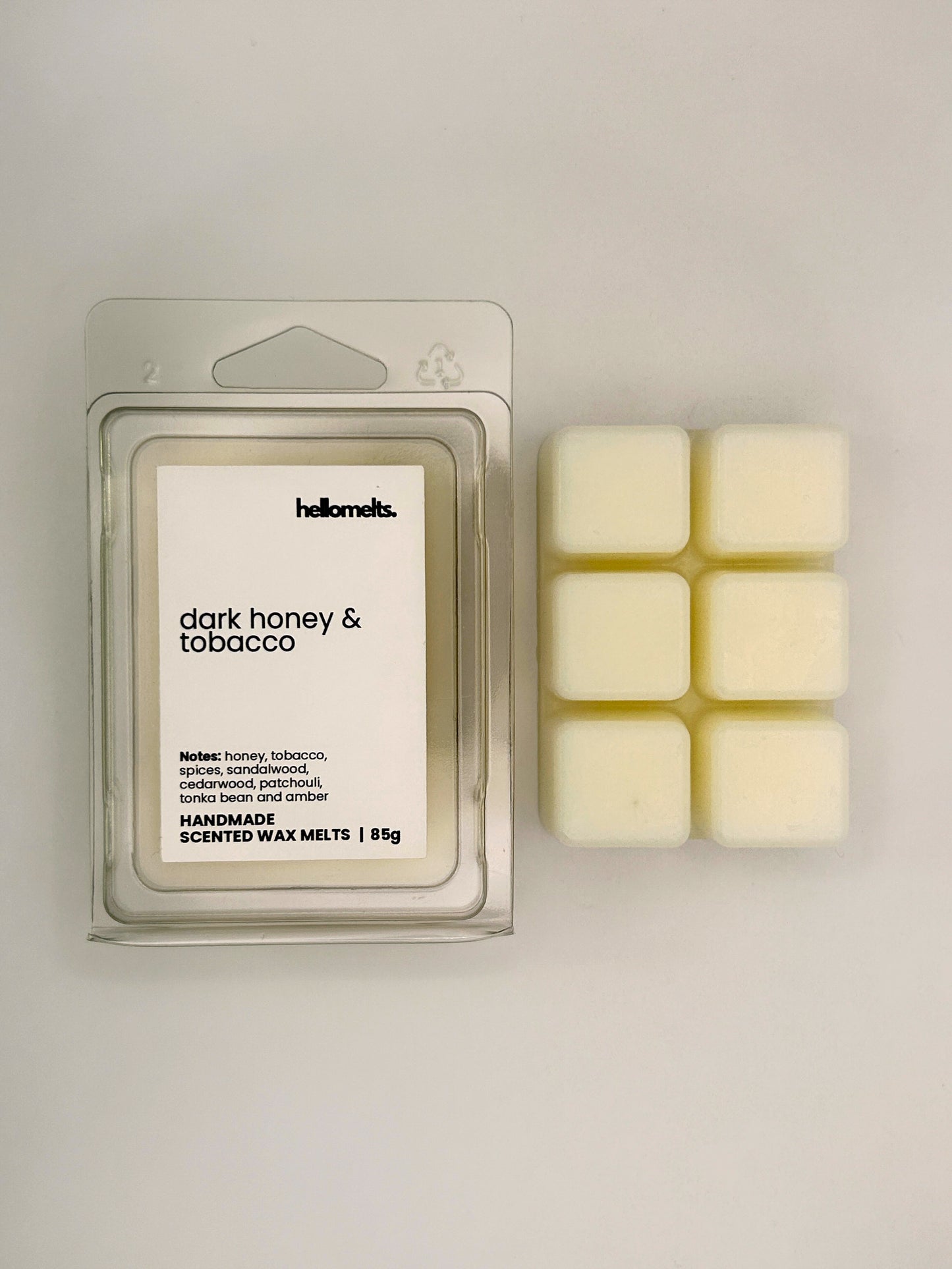 Dark Honey & Tobacco 85g wax melt bar displayed beside its clear clamshell packaging from the Hellomelts Autumn Collection