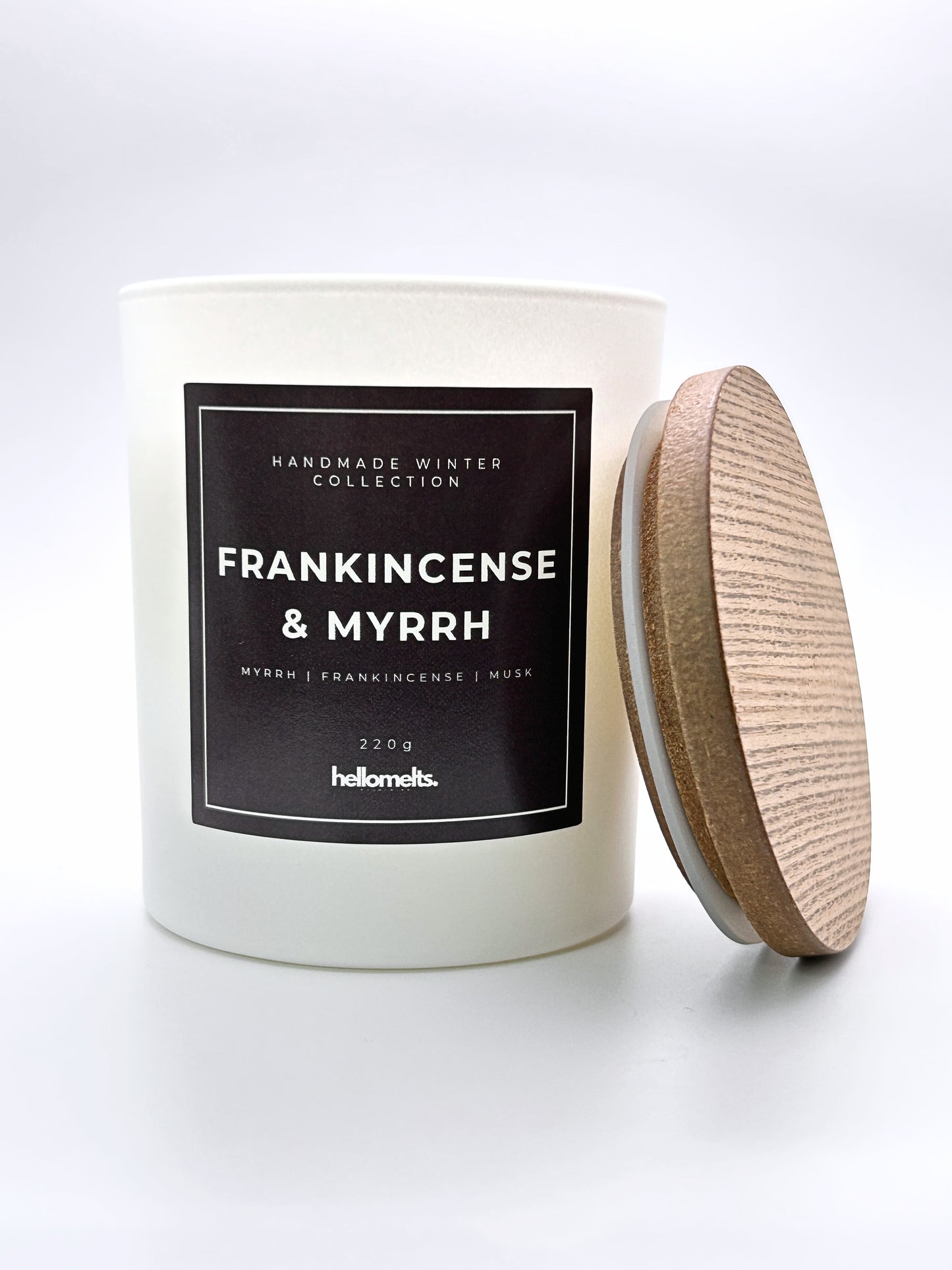 Frankincense & Myrrh 220g candle front-facing studio shot with the wooden lid positioned at the side, part of the Hellomelts Winter Collection