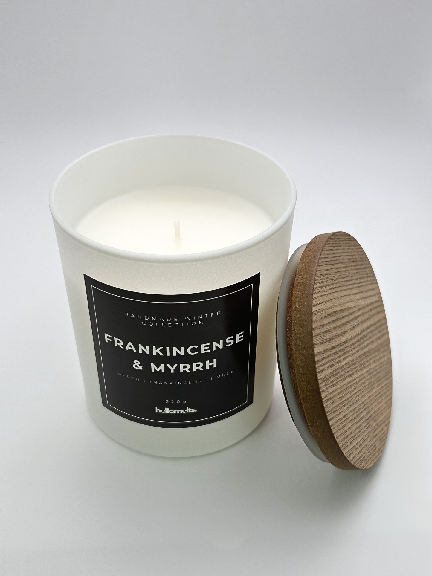 Frankincense & Myrrh 220g candle top-down view with the wooden lid placed beside the jar, part of the Hellomelts Winter Collection
