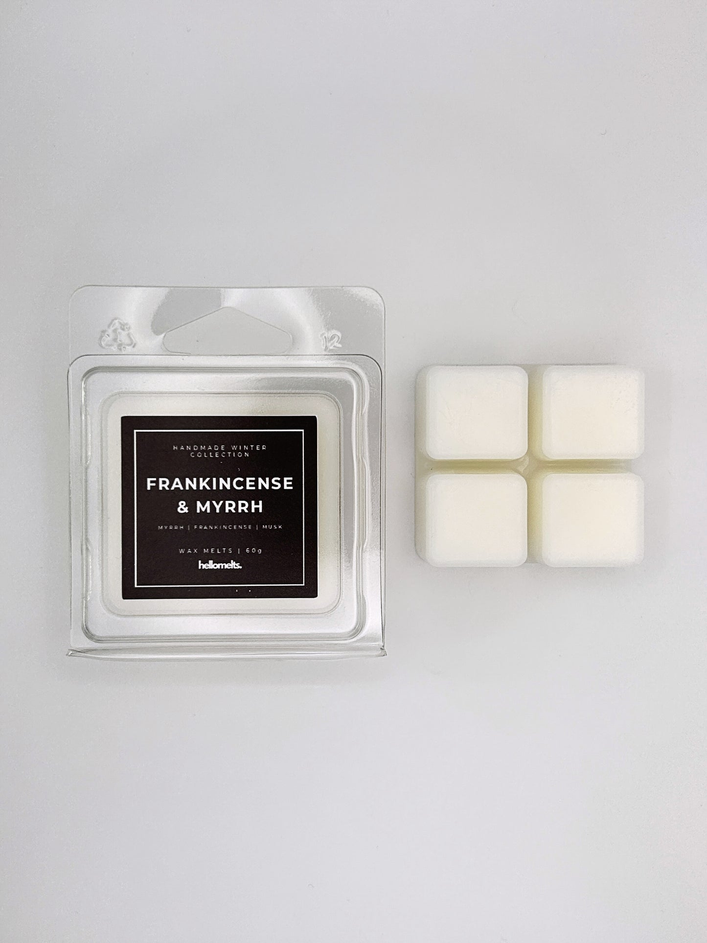 Frankincense & Myrrh 60g wax melt clamshell placed beside four wax cubes from the Hellomelts Winter Collection