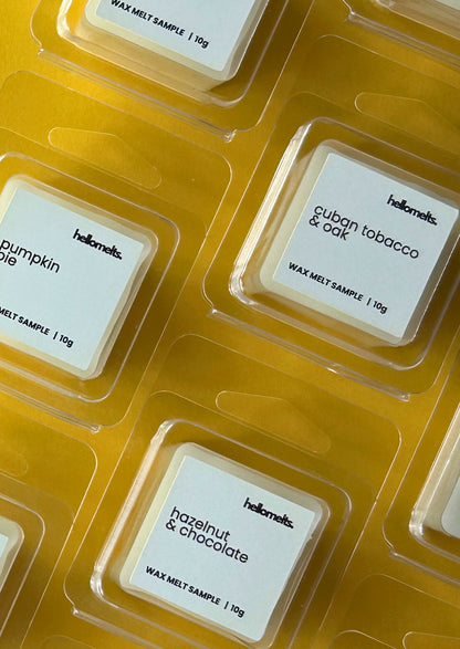 Close-up of Hellomelts Autumn Collection free 10g wax melt samples in clamshell packaging, featuring scents like Pumpkin Pie, Cuban Tobacco & Oak, and Hazelnut & Chocolate on a yellow background