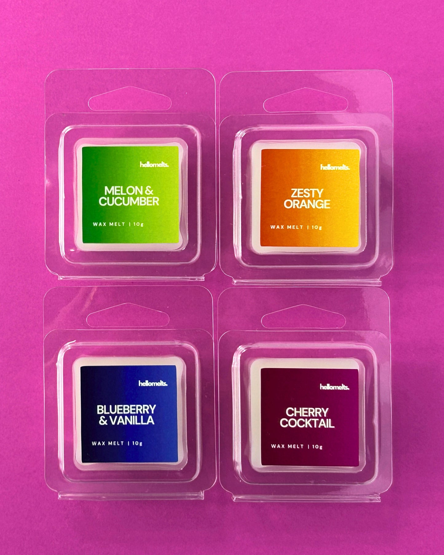 Set of free 10g wax melt samples in clamshell packaging from Hellomelts Summer Collection, featuring Melon & Cucumber, Zesty Orange, Blueberry & Vanilla, and Cherry Cocktail, displayed on a pink background