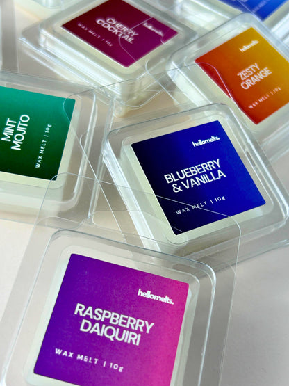 Close-up angled display of free 10g wax melt samples from Hellomelts Summer Collection, including Raspberry Daiquiri, Blueberry & Vanilla, Mint Mojito, Cherry Cocktail, and Zesty Orange, in clamshell packaging on a light background