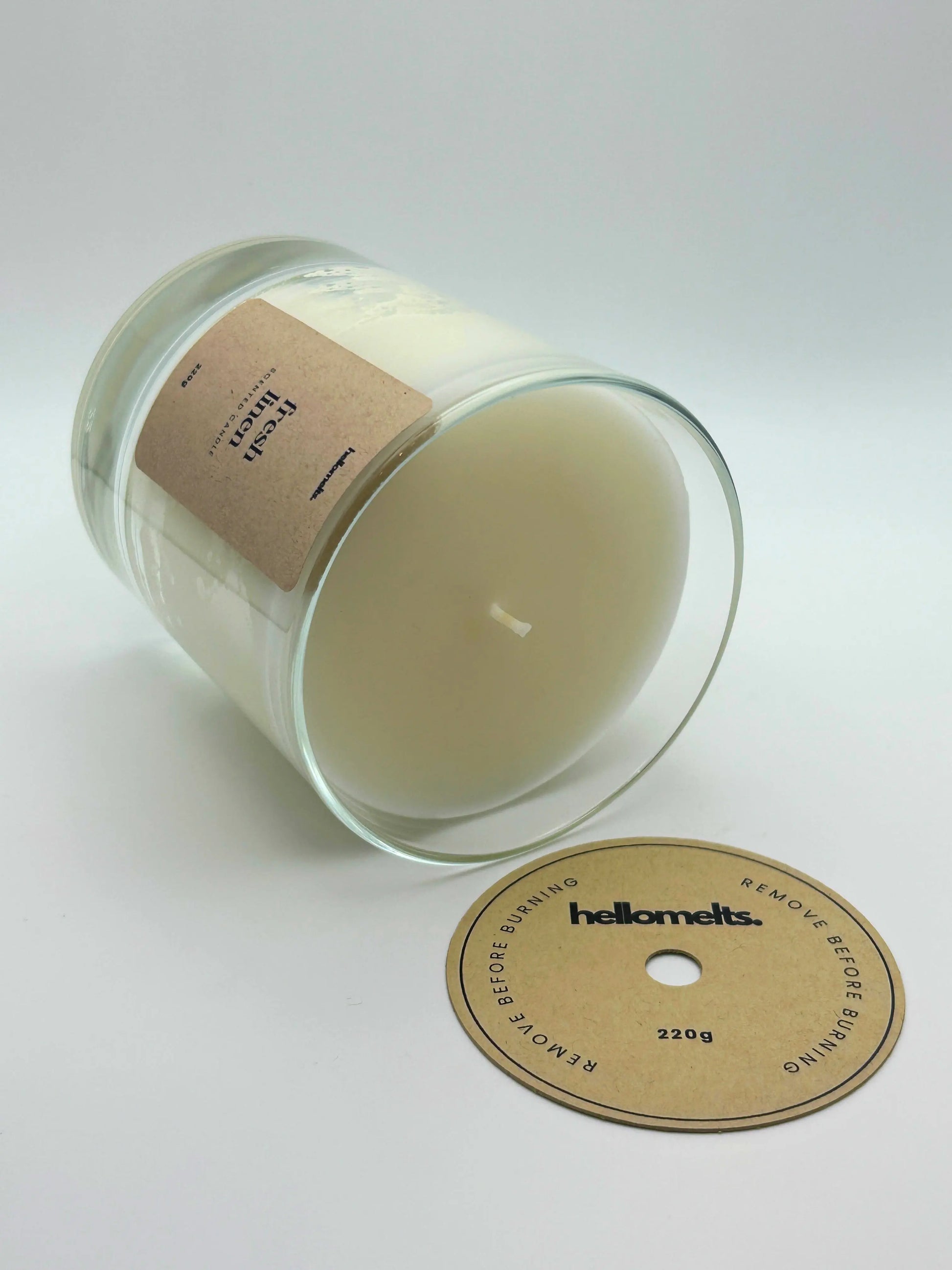 Fresh Linen candle lying flat with the wick cover removed and placed beside it, showing the smooth wax finish by Hellomelts.