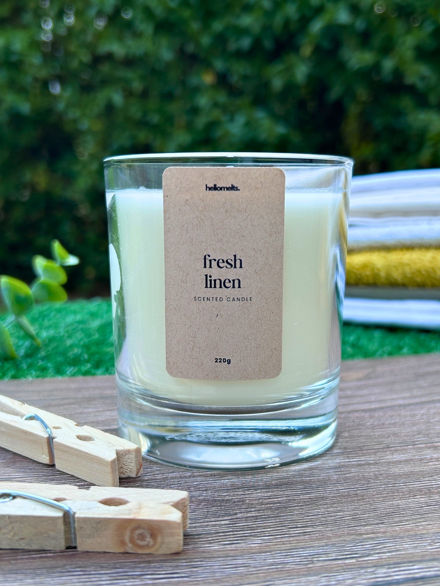 Fresh Linen scented candle by Hellomelts, shown in an outdoor spring setting with wooden pegs and soft natural textures, highlighting the clean, airy character of this Spring Collection fragrance