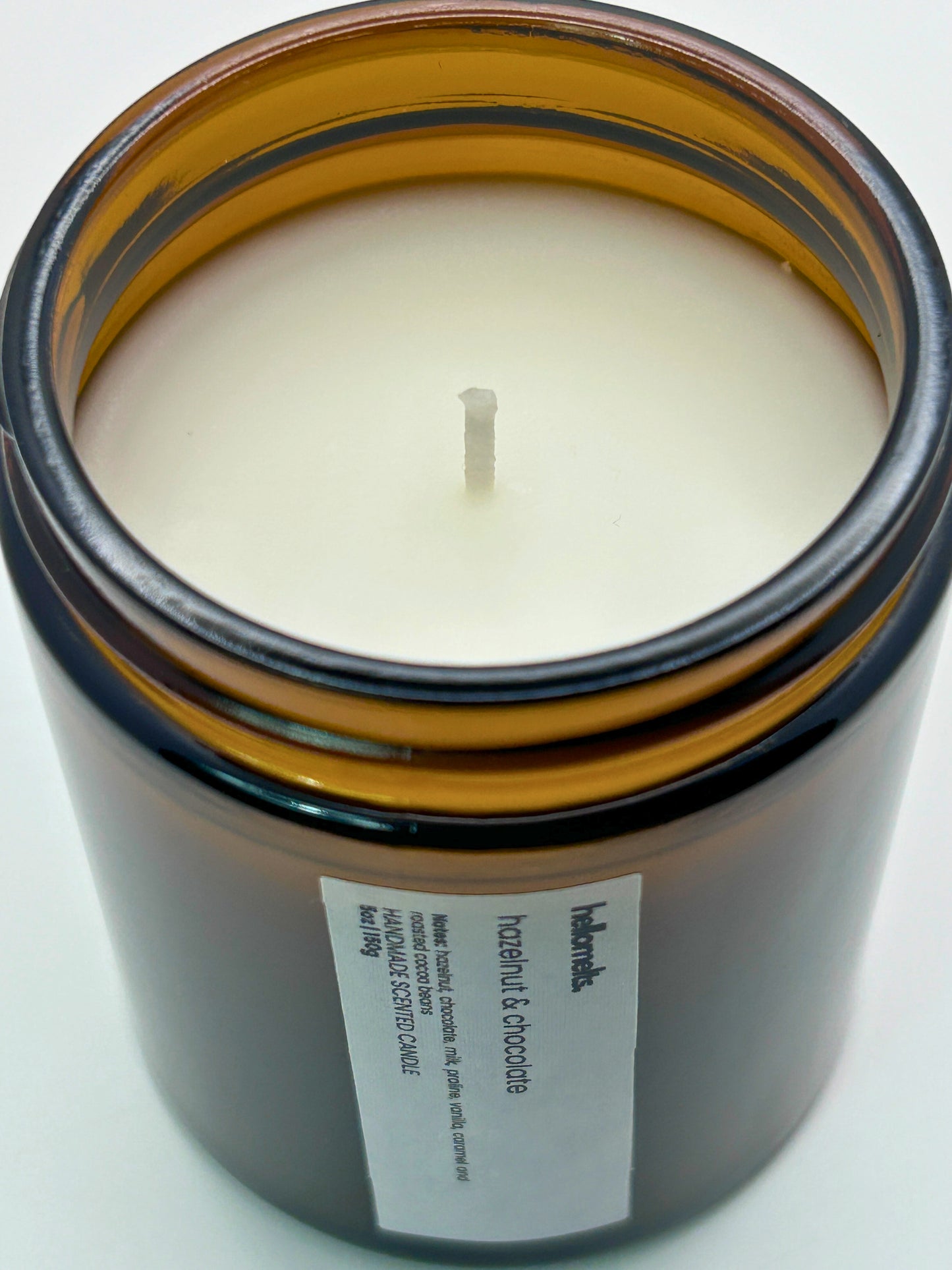 Close-up angled top-down view of Hazelnut & Chocolate autumn scented candle by Hellomelts, showcasing the smooth wax in an amber jar from the Autumn Collection