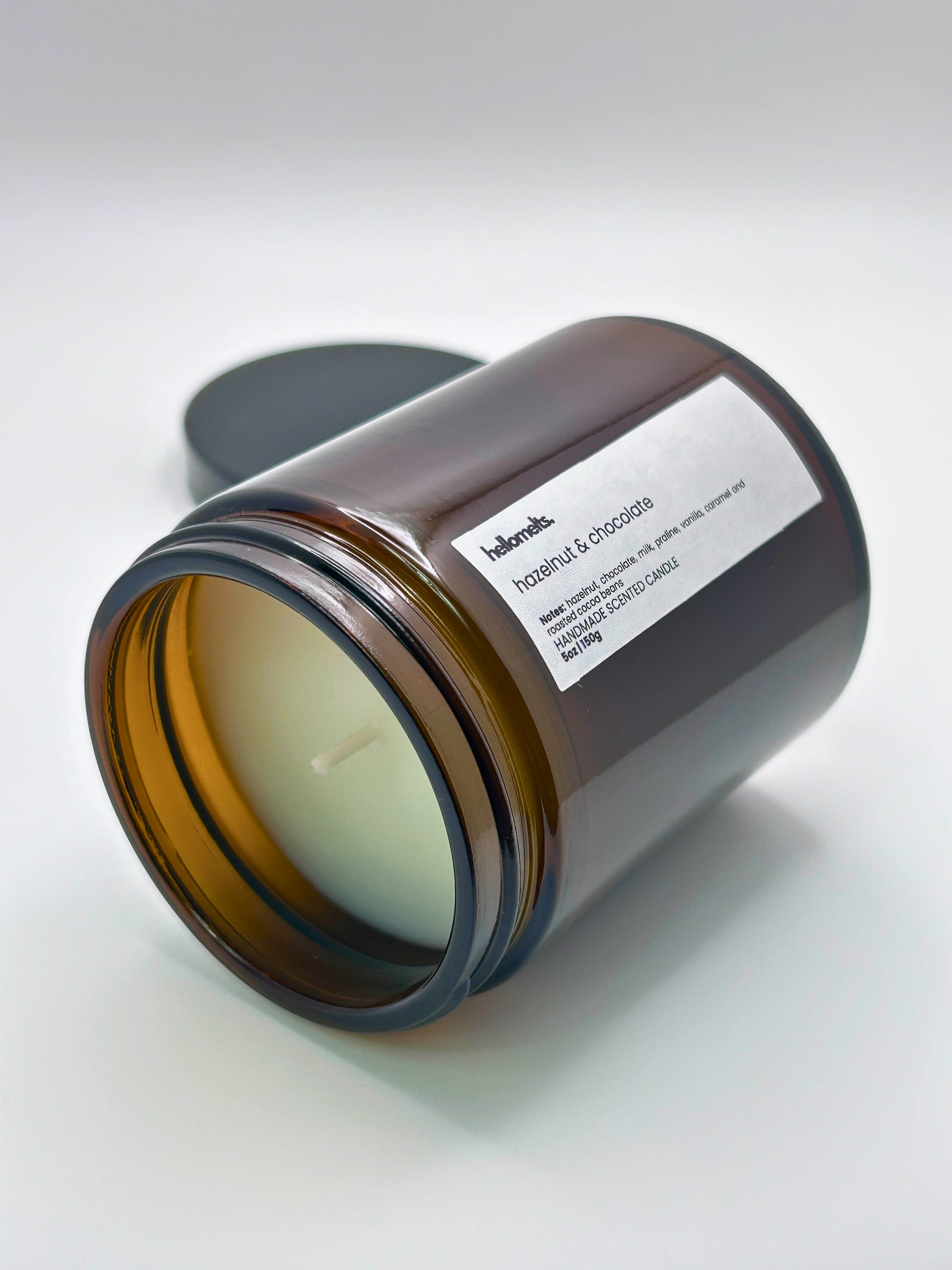 Hazelnut & Chocolate autumn scented candle by Hellomelts lying on its side with the wick facing forward, part of the Autumn Collection