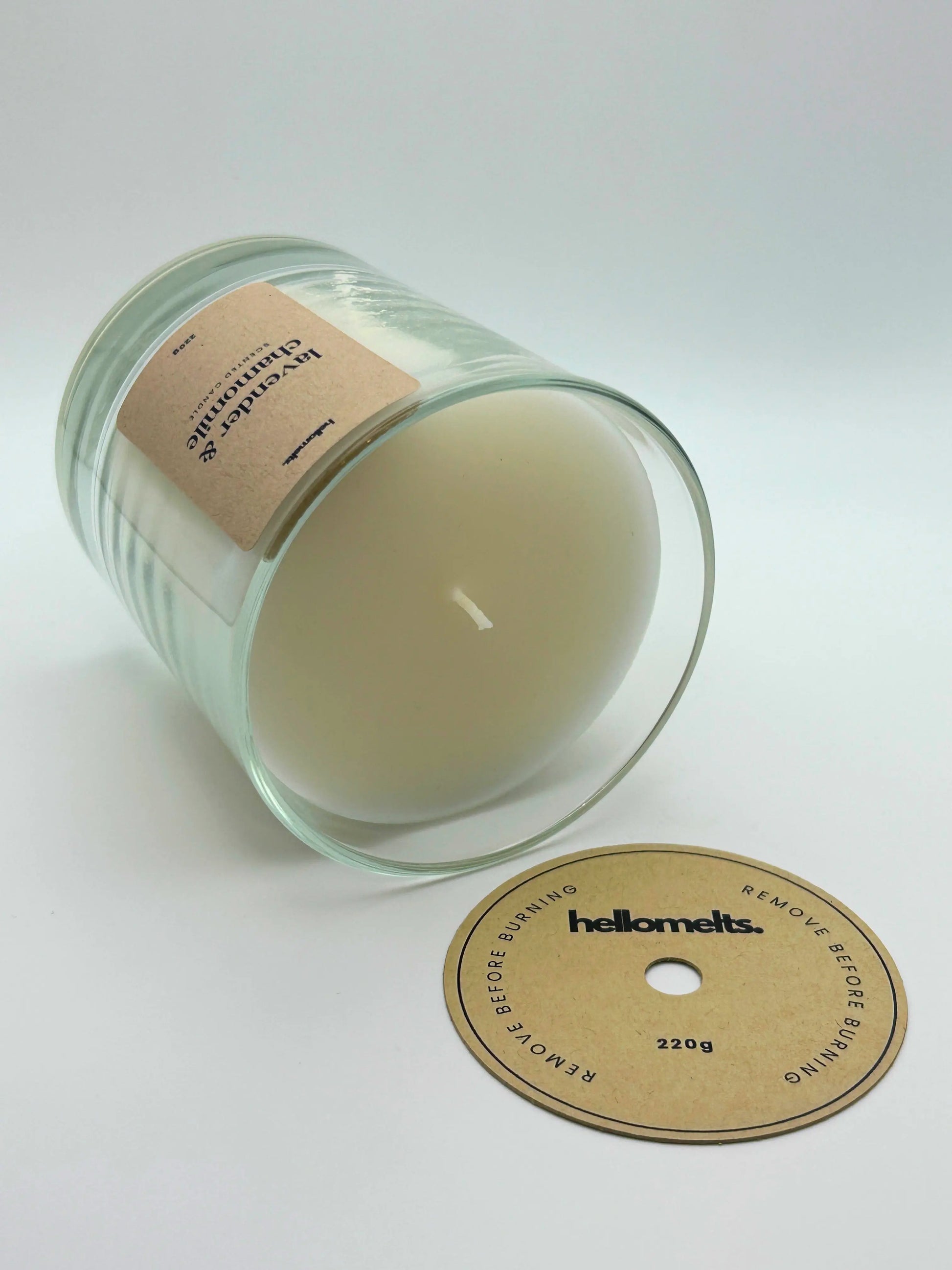 Lavender & Chamomile candle lying flat with the wick cover removed and placed beside it, showing the smooth wax finish by Hellomelts.
