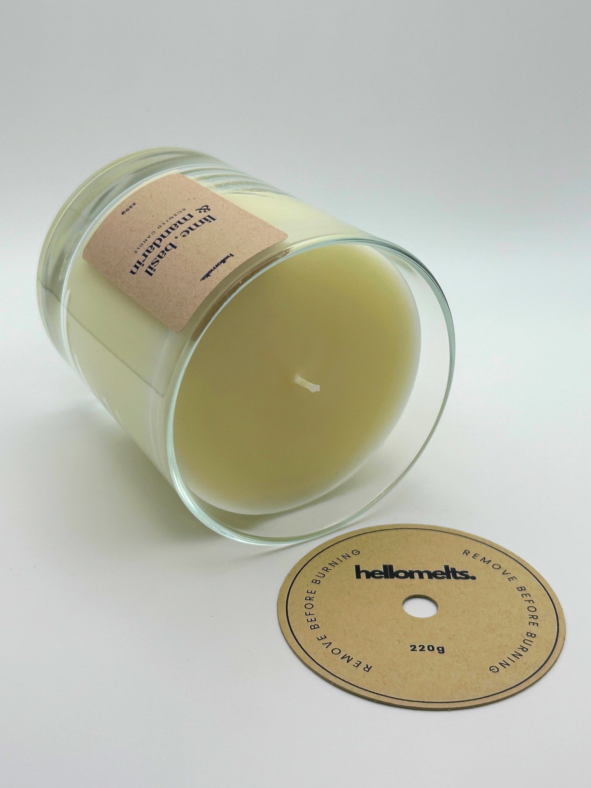 Lime, Basil & Mandarin candle lying flat with the wick cover removed and placed beside it, showing the smooth wax finish by Hellomelts.