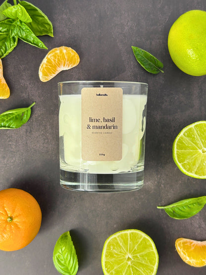 Lime Basil and Mandarin scented candle by Hellomelts styled in a flatlay with fresh basil leaves lime and mandarin on a dark textured background from the Spring Collection