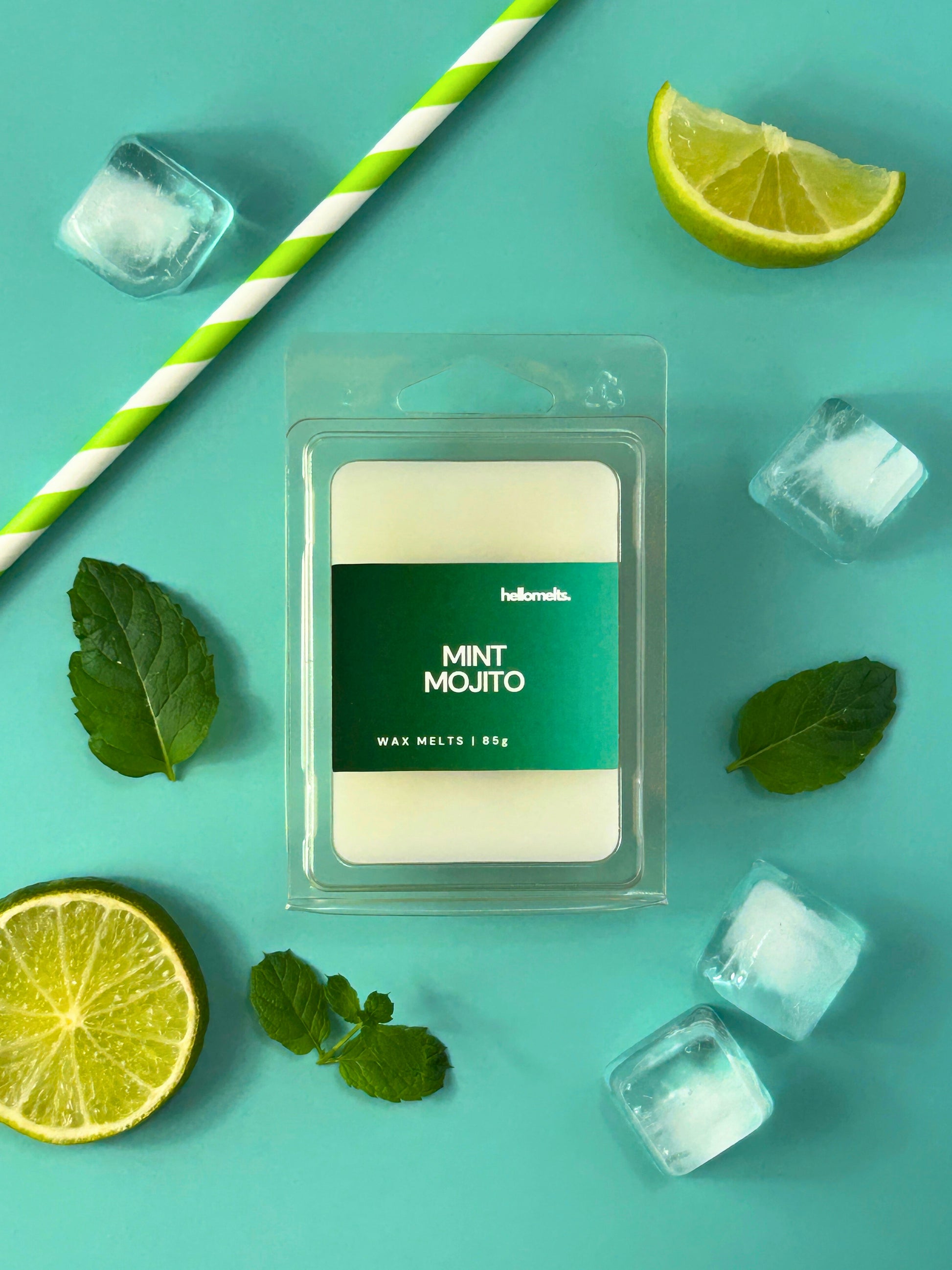 Mint Mojito wax melt bar by Hellomelts, shown in clear clamshell packaging with fresh mint leaves, lime slices and ice cubes on a turquoise background from the Summer Collection