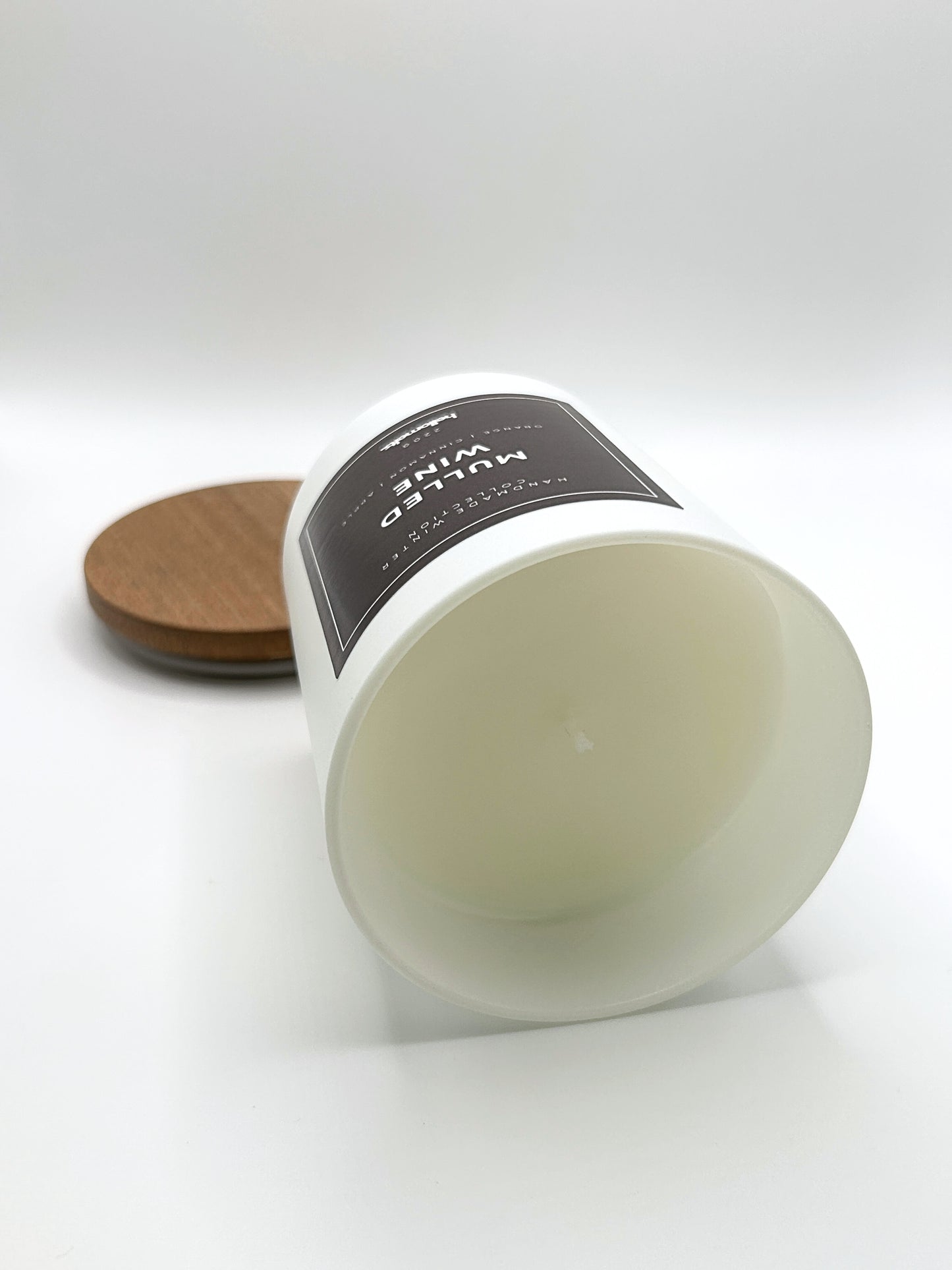 Mulled Wine 220g candle laid on its side with the lid in the background, showing the matte white jar from the Hellomelts Winter Collection