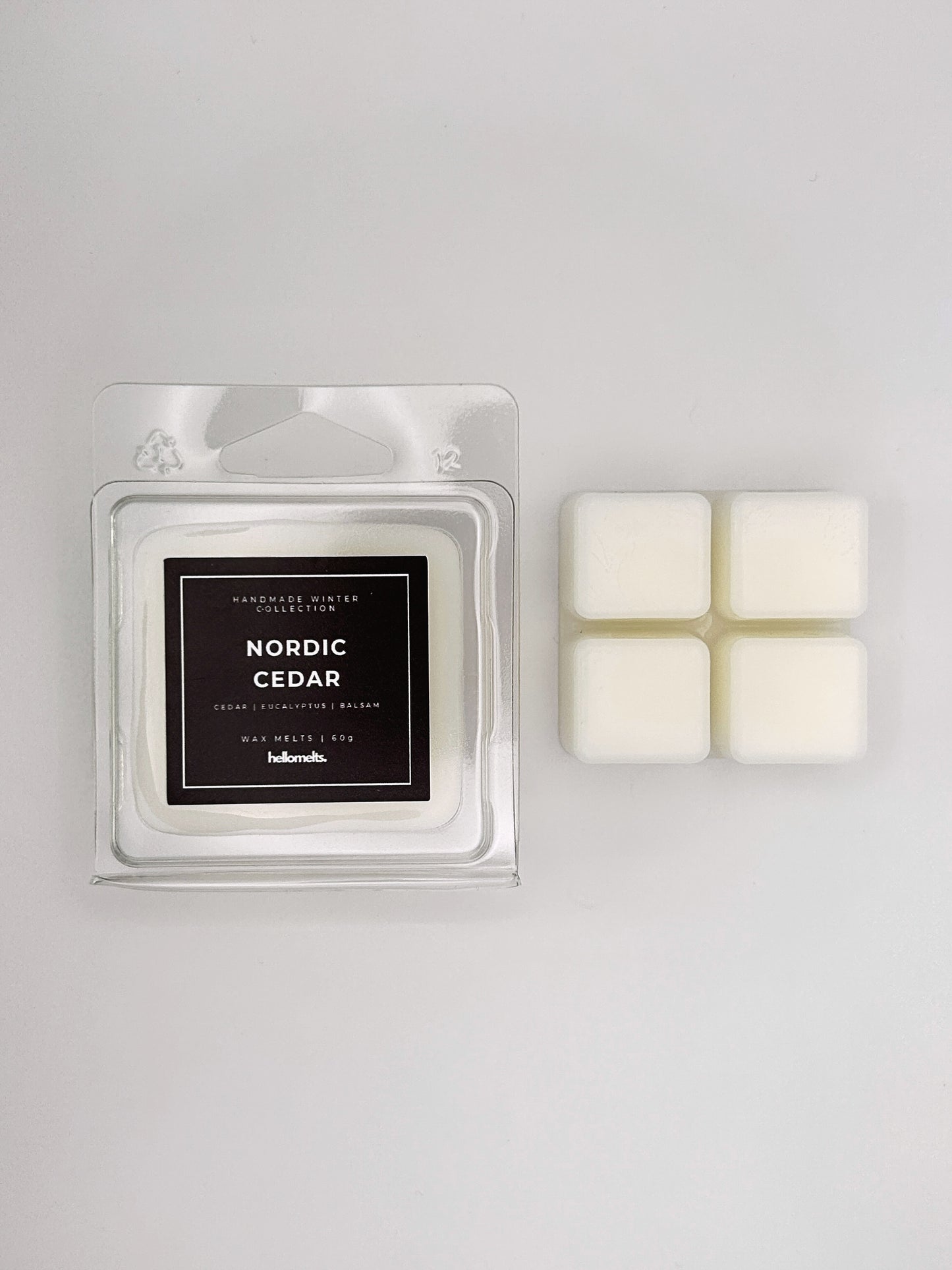 Nordic Cedar 60g wax melt clamshell placed beside four wax cubes from the Hellomelts Winter Collection