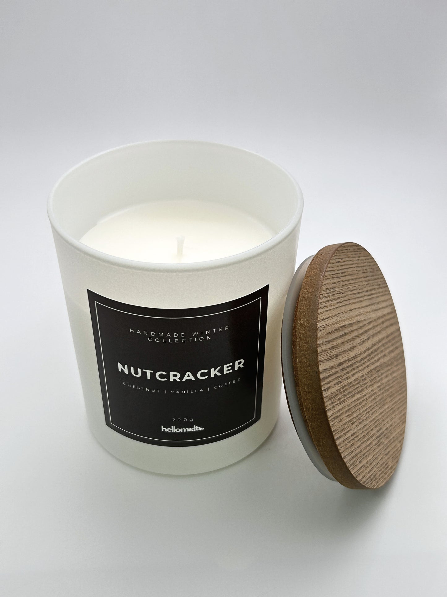 Nutcracker 220g candle top-down view with the wooden lid placed beside the jar, part of the Hellomelts Winter Collection