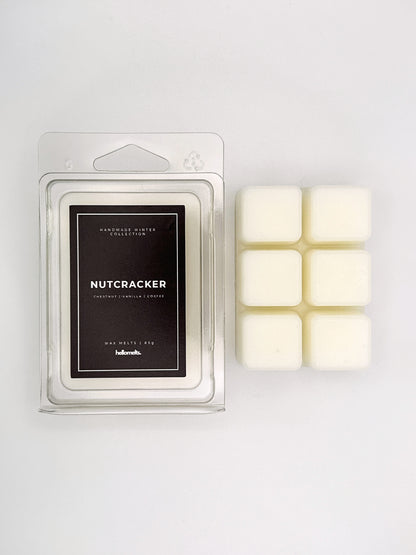 Nutcracker 85g wax melt clamshell placed beside six wax cubes from the Hellomelts Winter Collection