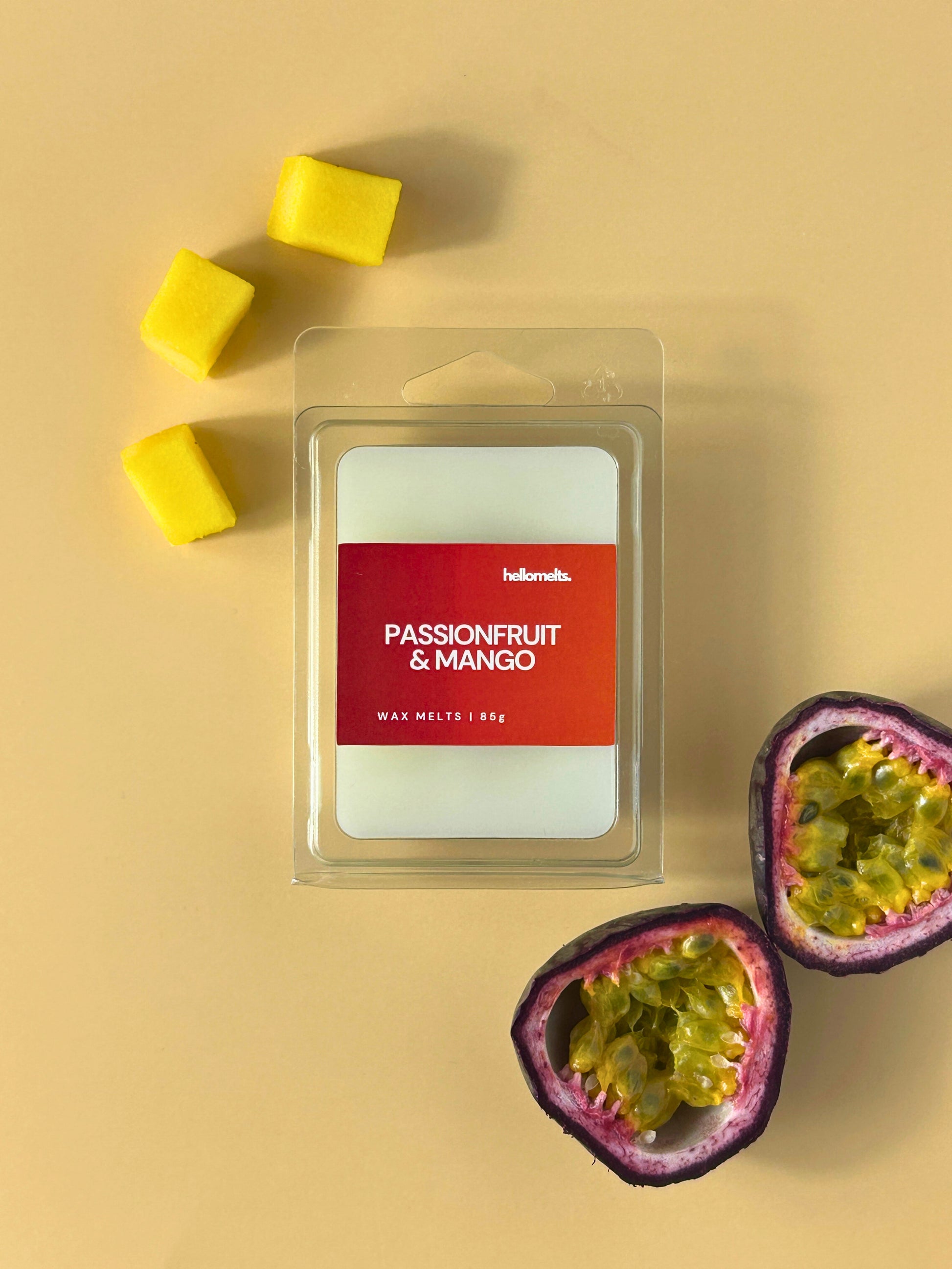 Passionfruit & Mango wax melts by Hellomelts, shown in clear clamshell packaging on a warm neutral background with fresh passionfruit halves and mango cubes, from the Summer Collection