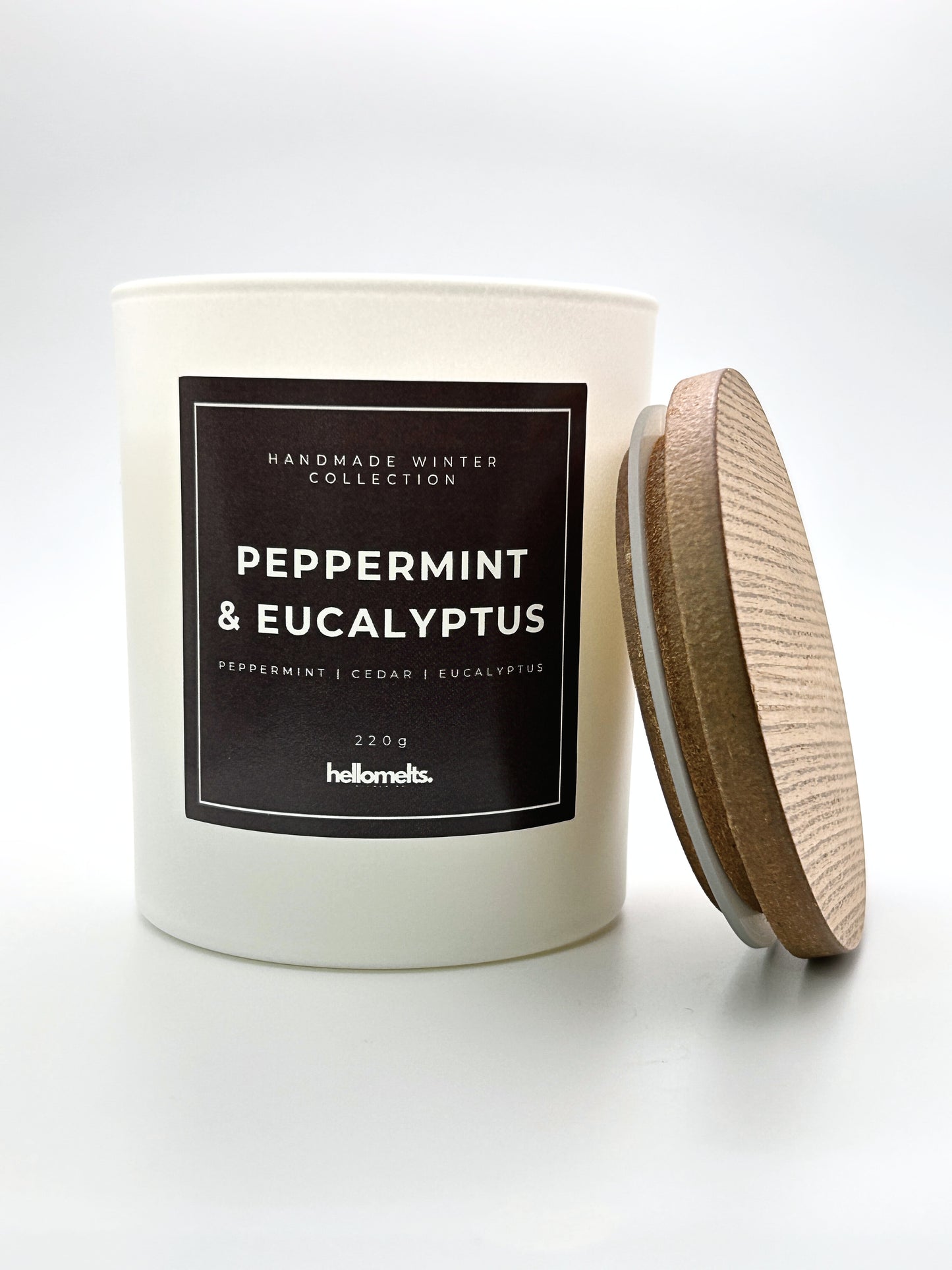 Peppermint & Eucalyptus 220g candle front-facing studio shot with the wooden lid positioned at the side, part of the Hellomelts Winter Collection