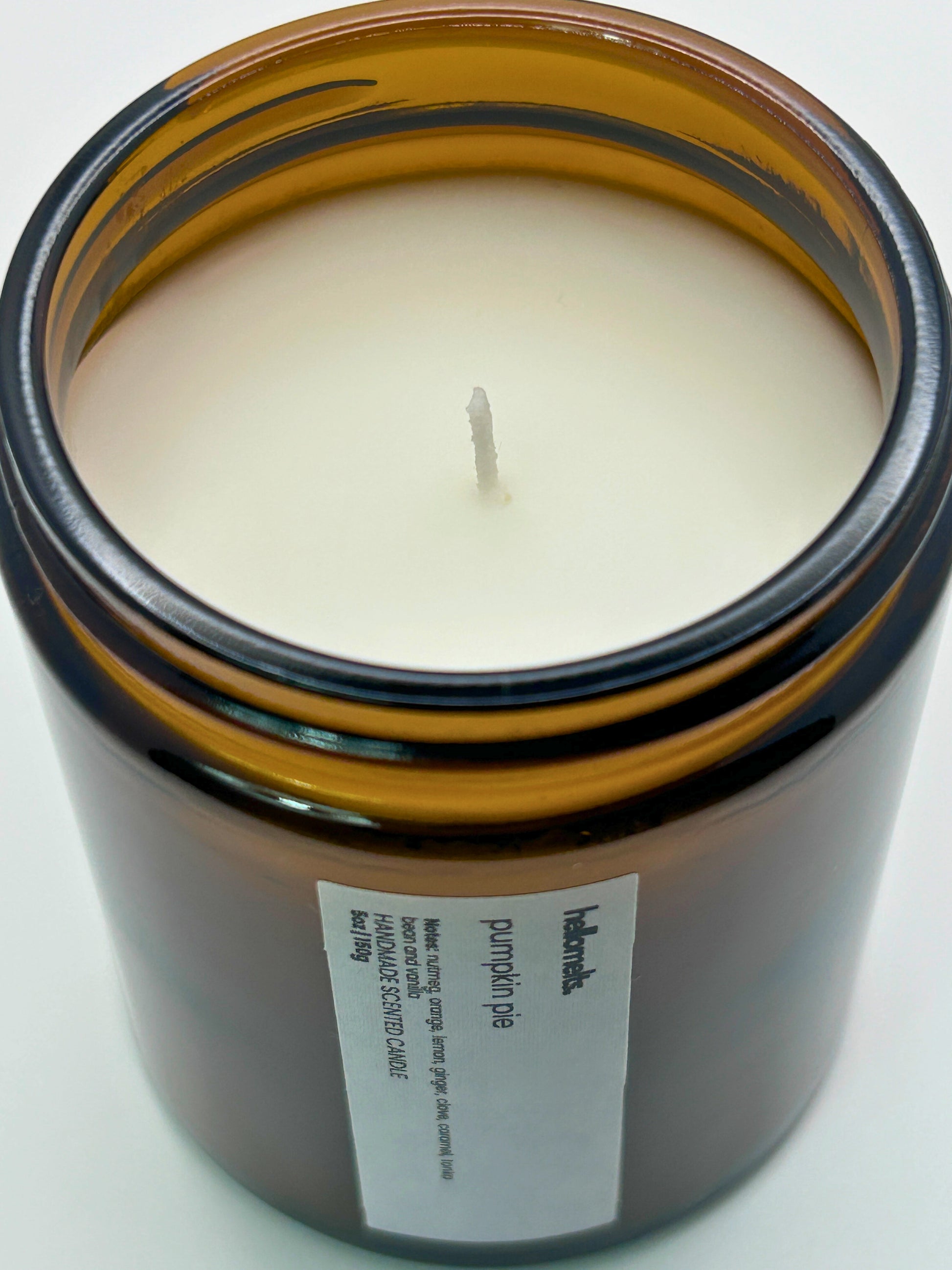 Close-up angled top-down view of Pumpkin Pie autumn scented candle by Hellomelts, showcasing the smooth wax in an amber jar from the Autumn Collection