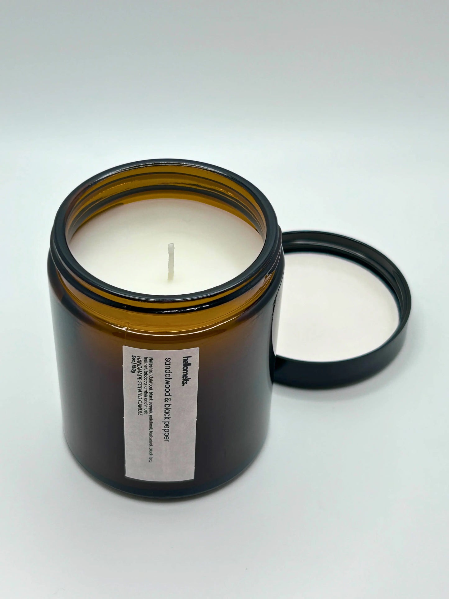 Angled view of Sandalwood & Black Pepper candle by Hellomelts, showcasing the amber jar from the autumn collection.