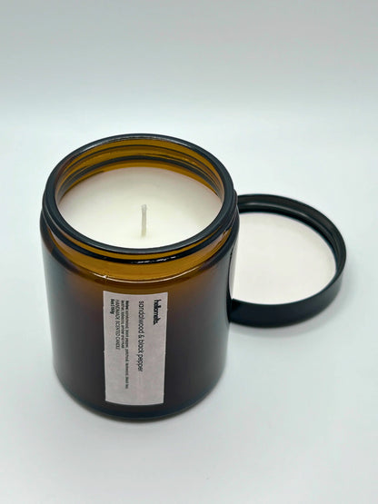 Angled view of Sandalwood & Black Pepper candle by Hellomelts, showcasing the amber jar from the autumn collection.
